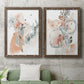 Set of two walnut barnwood framed canvas prints depicting a coordinated art pair of loose blush gray and coral floral gestures rendered as abstract watercolor botanicals above a sofa in a modern living room.