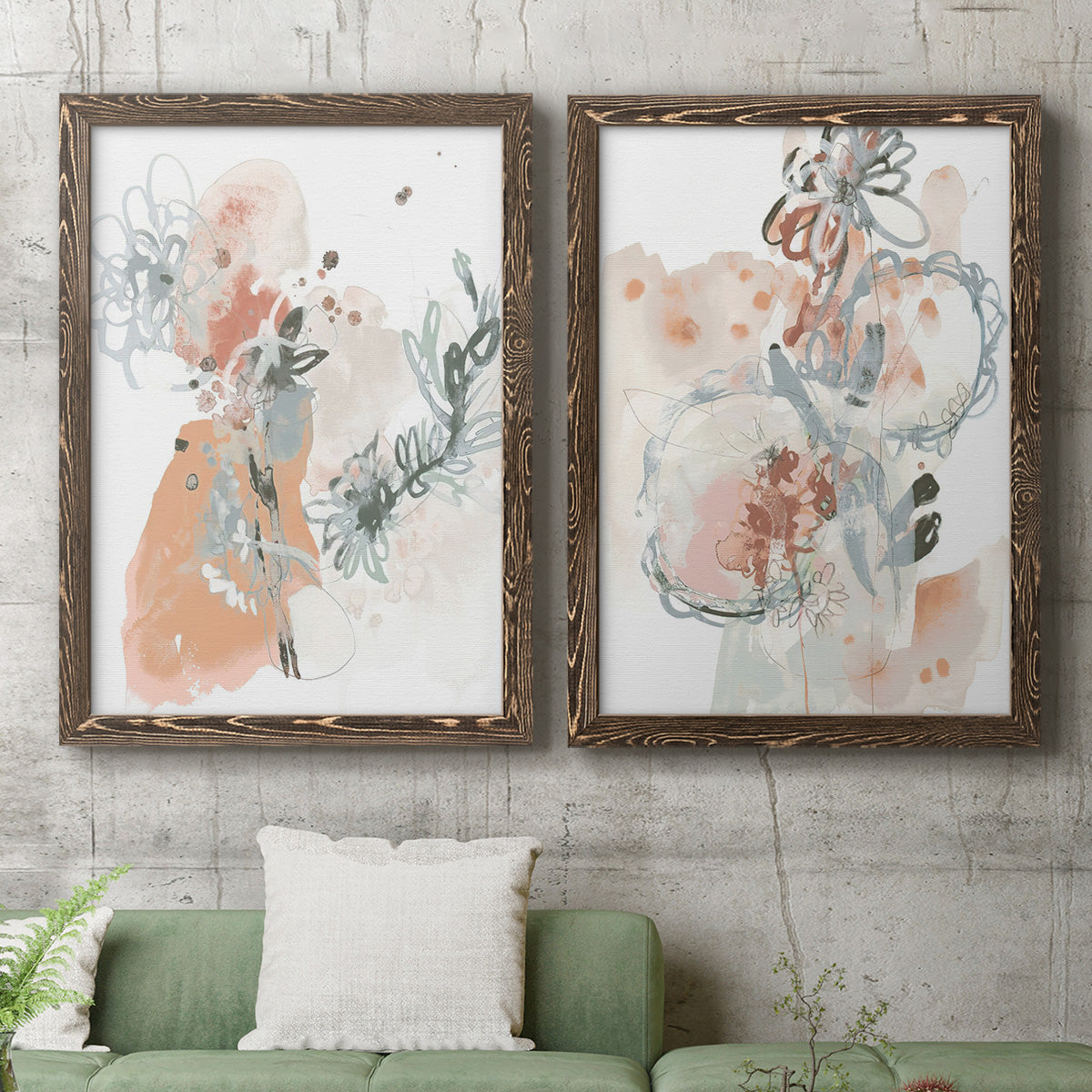 Set of two walnut barnwood framed canvas prints depicting a coordinated art pair of loose blush gray and coral floral gestures rendered as abstract watercolor botanicals above a sofa in a modern living room.
