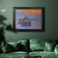 Impressionist haystack scene at sunset by Claude Monet in an ornate black frame with gilded inner detail displayed in a dark-toned interior setting.