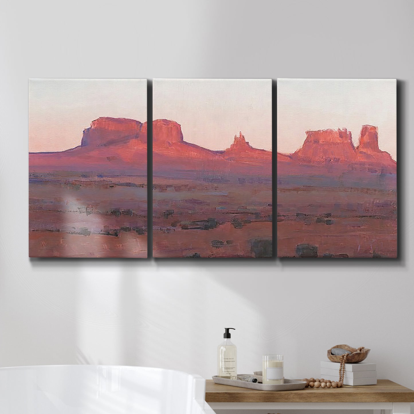 Three-panel canvas wall art featuring red rock desert formations at dusk, displayed in a bathroom above a bathtub.