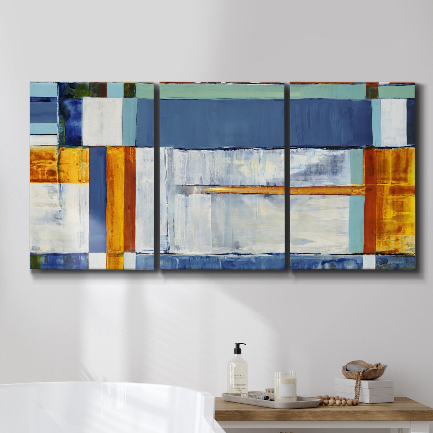Three-panel canvas wall art featuring bright mid century geometric abstraction, displayed in a bathroom above a bathtub.