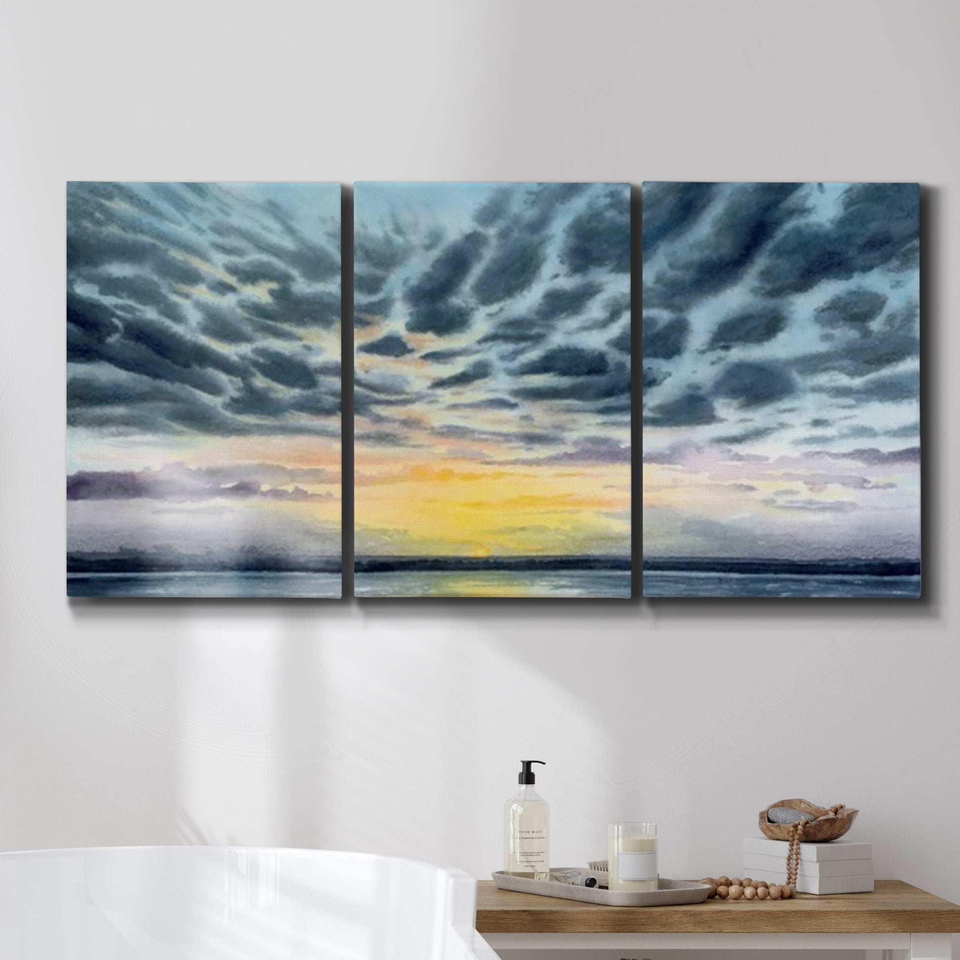 Three-panel canvas wall art featuring tropical coastal sunset over water, displayed in a bathroom above a bathtub.