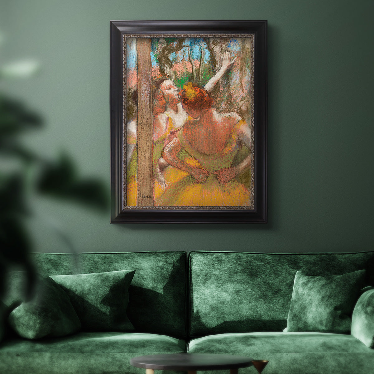 Impressionist ballet dancer composition by Edgar Degas in an ornate black frame with gilded inner detail displayed in a dark-toned interior setting.