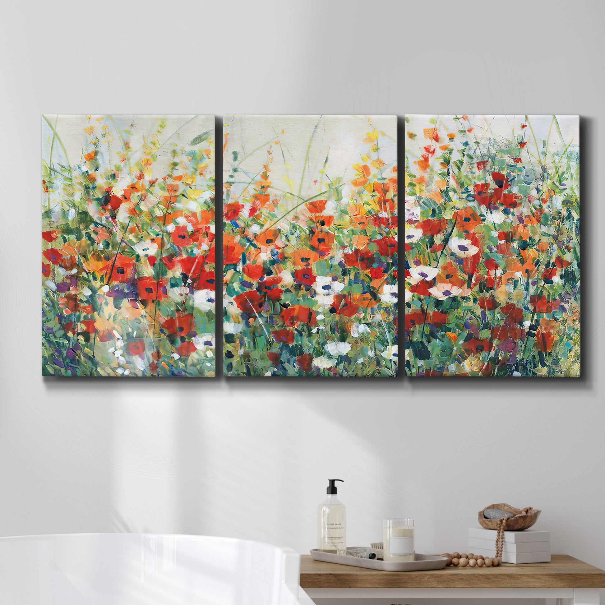 Three-panel canvas wall art featuring colorful garden flowers in bloom, displayed in a bathroom above a bathtub.