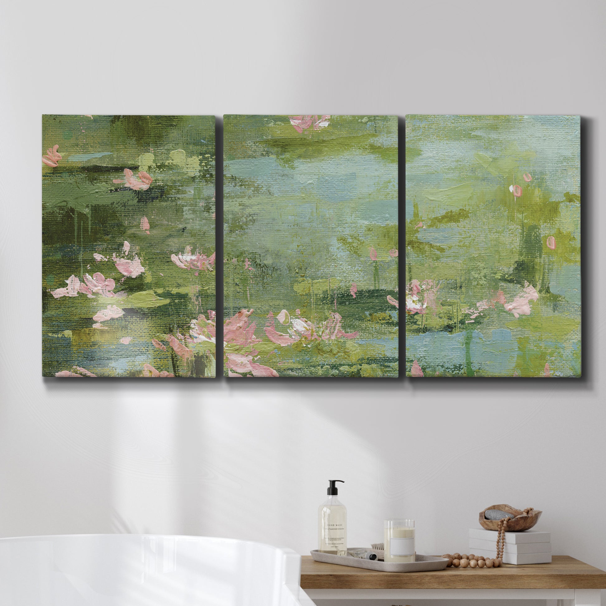 Three-panel canvas wall art featuring muted water lily pond, displayed in a bathroom above a bathtub.