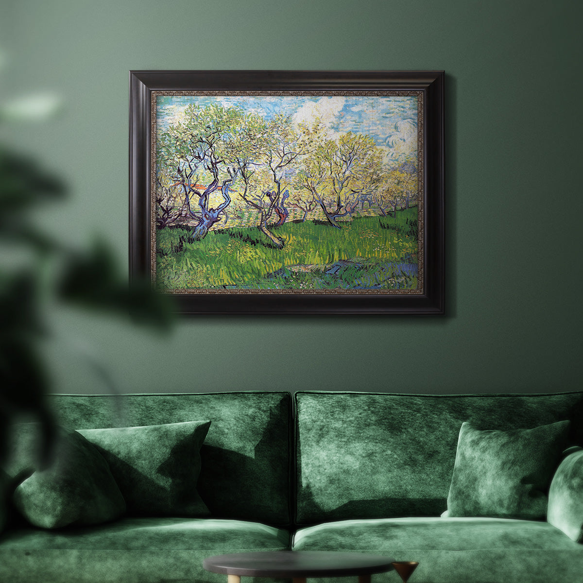 Impressionist spring orchard landscape by Vincent van Gogh in an ornate black frame with gilded inner detail displayed in a dark-toned interior setting.