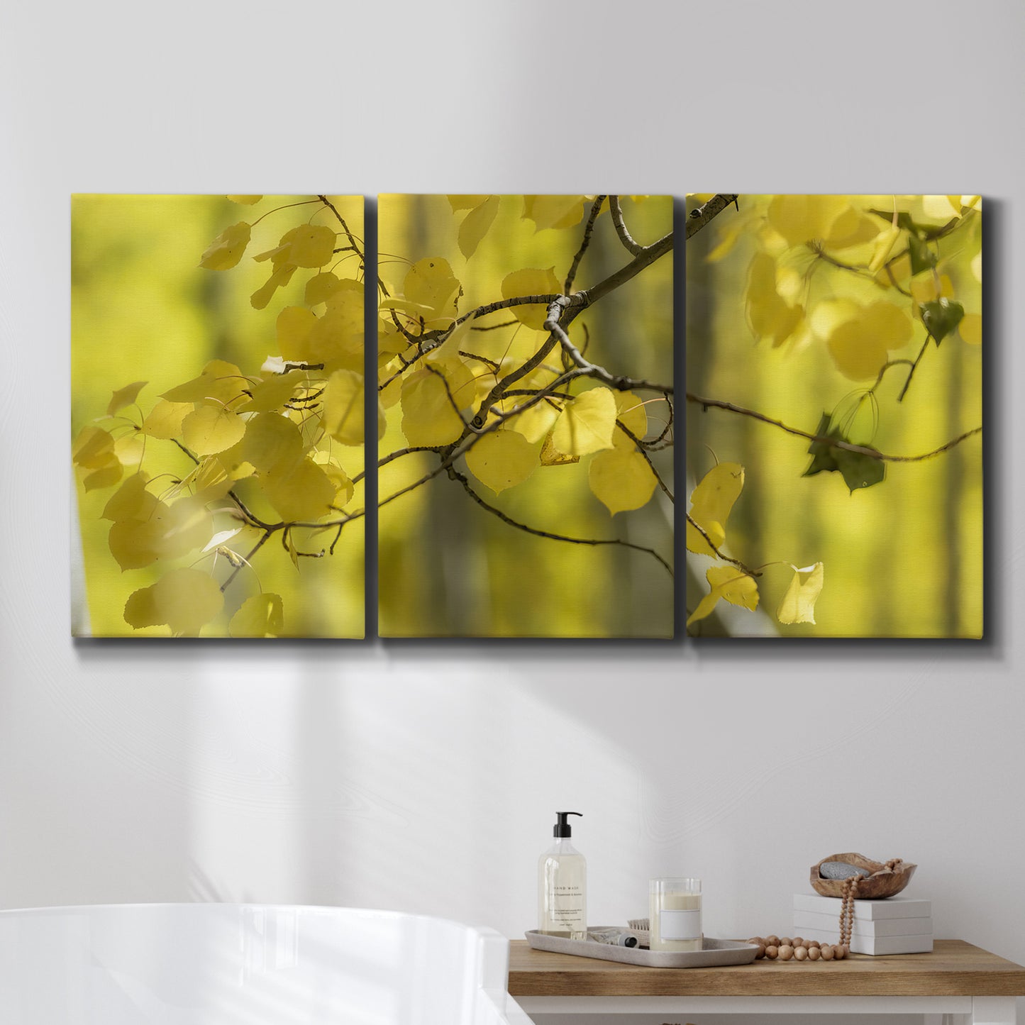 Three-panel canvas wall art featuring backlit aspen trees photograph, displayed in a bathroom above a bathtub.