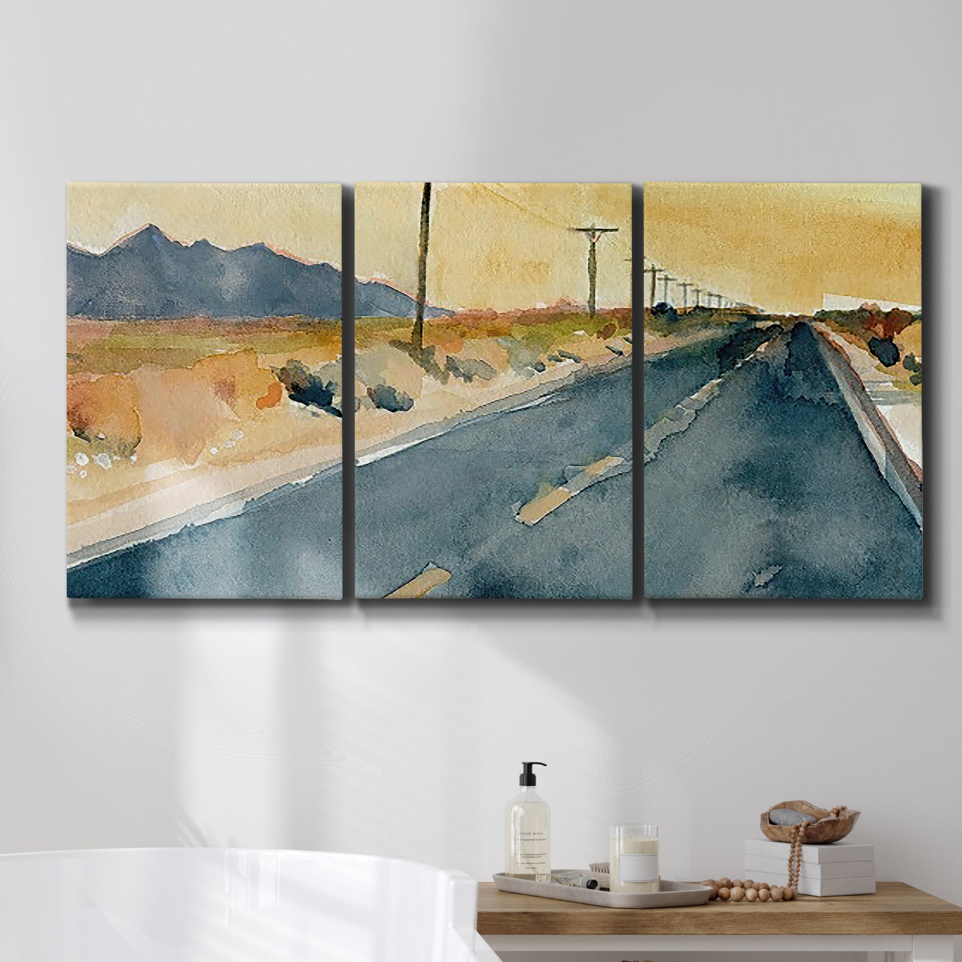 Three-panel canvas wall art featuring empty highway stretching through landscape, displayed in a bathroom above a bathtub.