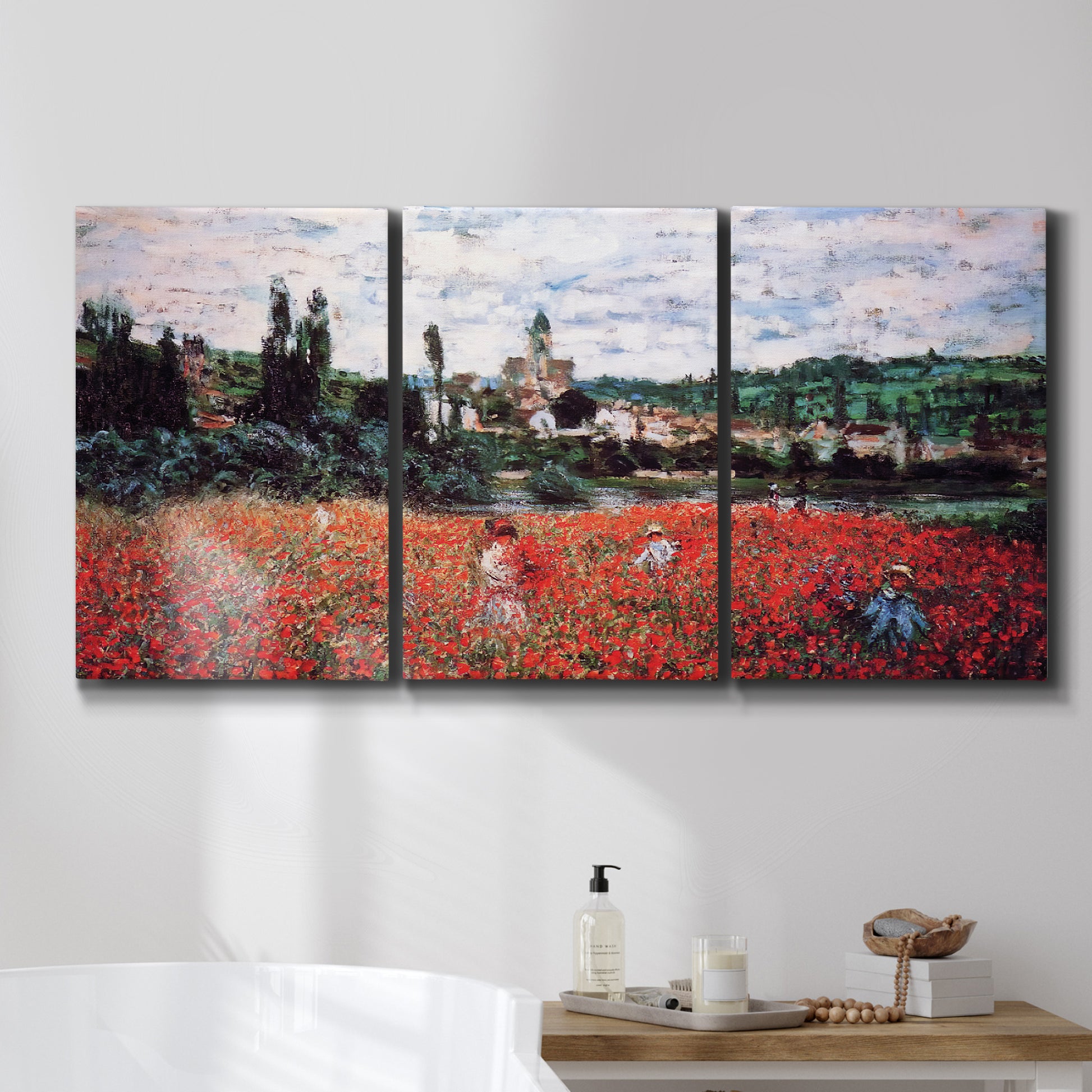 Three-panel canvas wall art featuring poppy field beside village landscape, displayed in a bathroom above a bathtub.