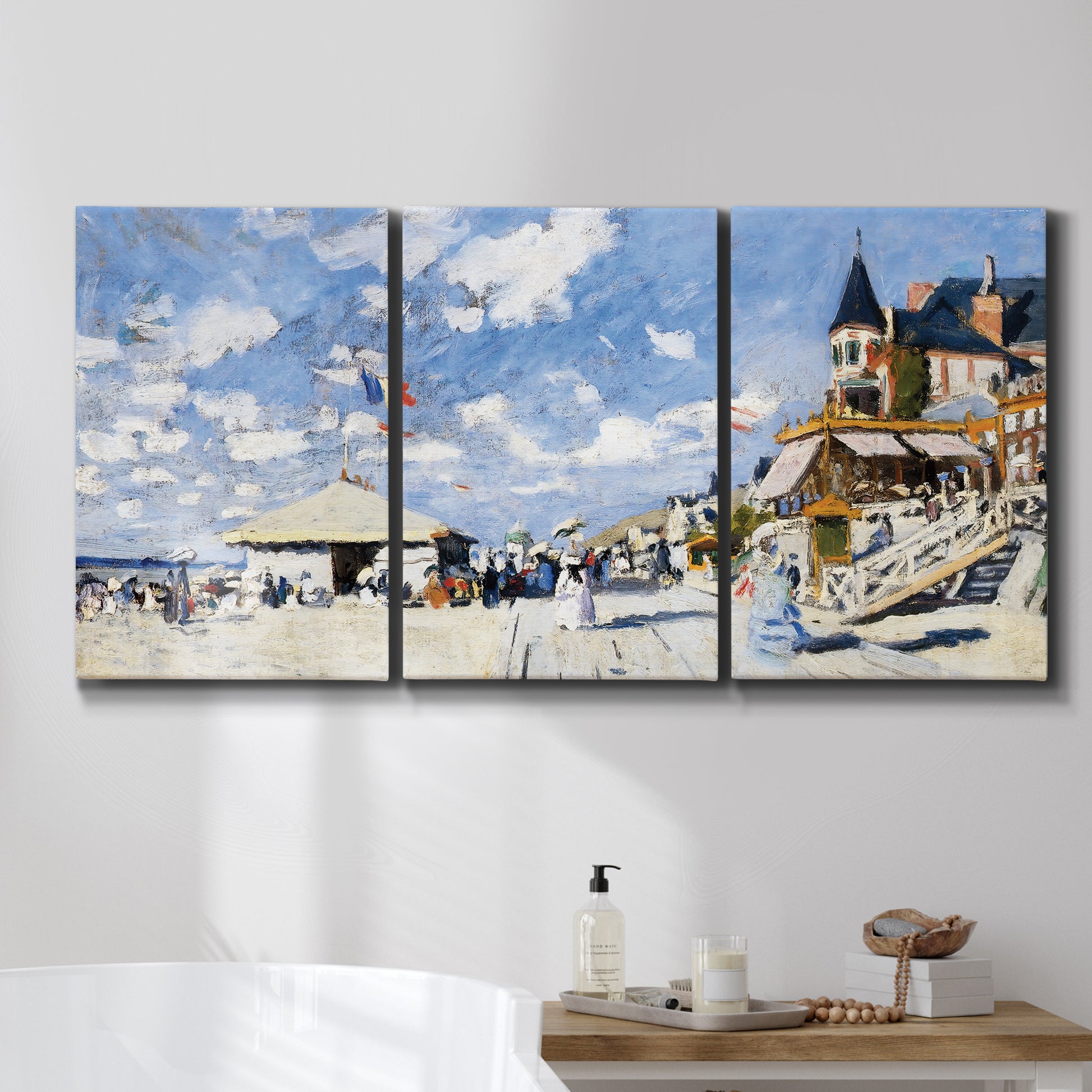 Three-panel canvas wall art featuring beach boardwalk with figures, displayed in a bathroom above a bathtub.