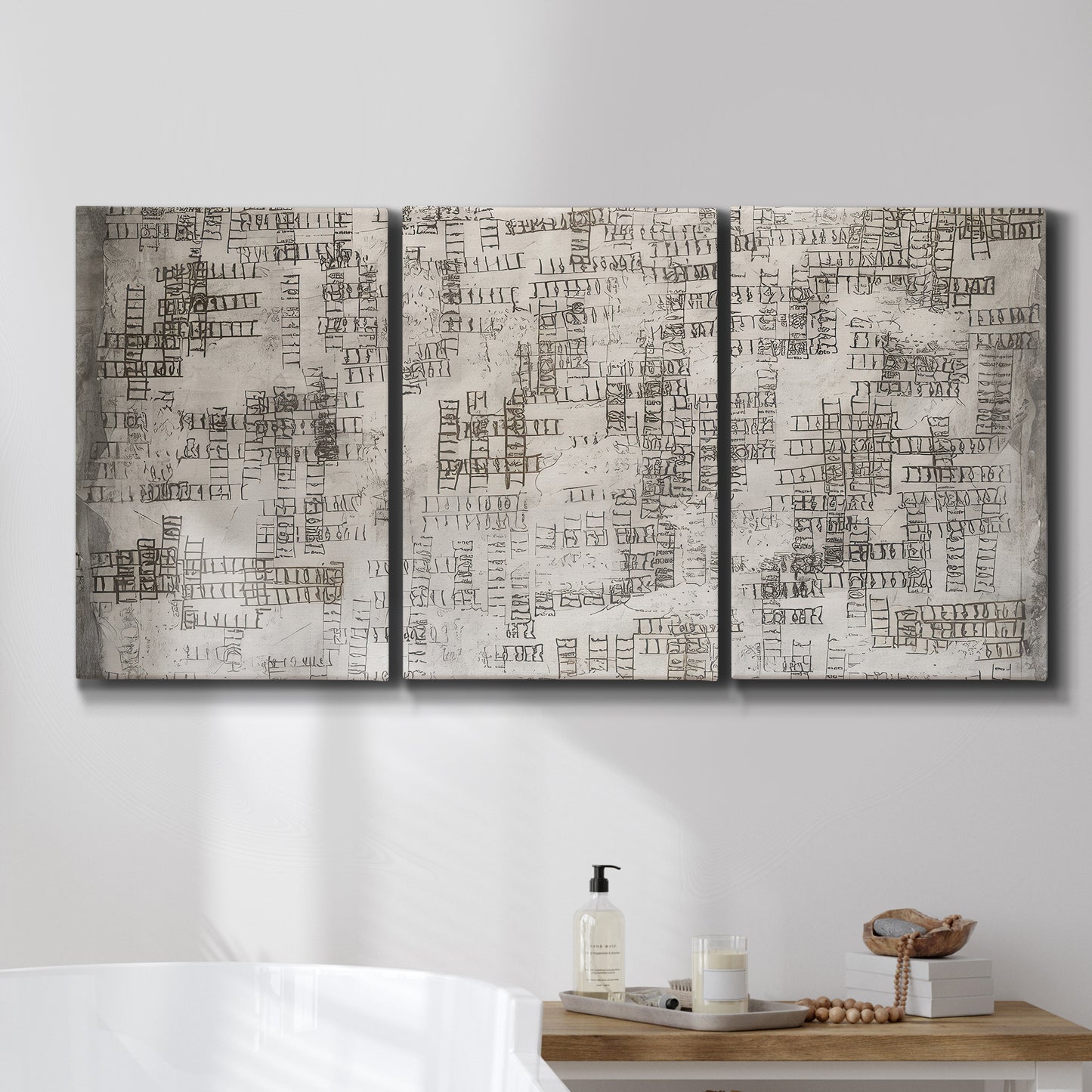 Three-panel canvas wall art featuring grid based geometric abstraction, displayed in a bathroom above a bathtub.