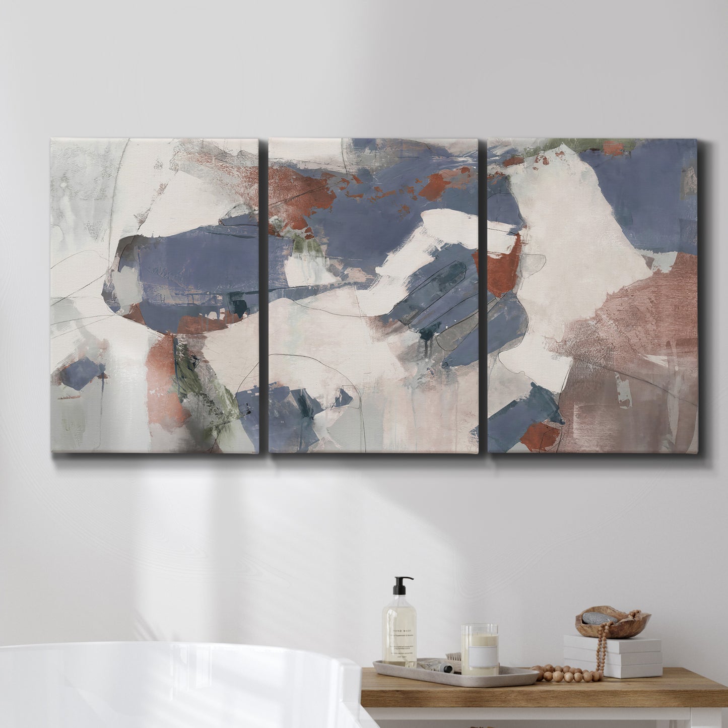 Three-panel canvas wall art featuring cool blue abstract layered composition, displayed in a bathroom above a bathtub.