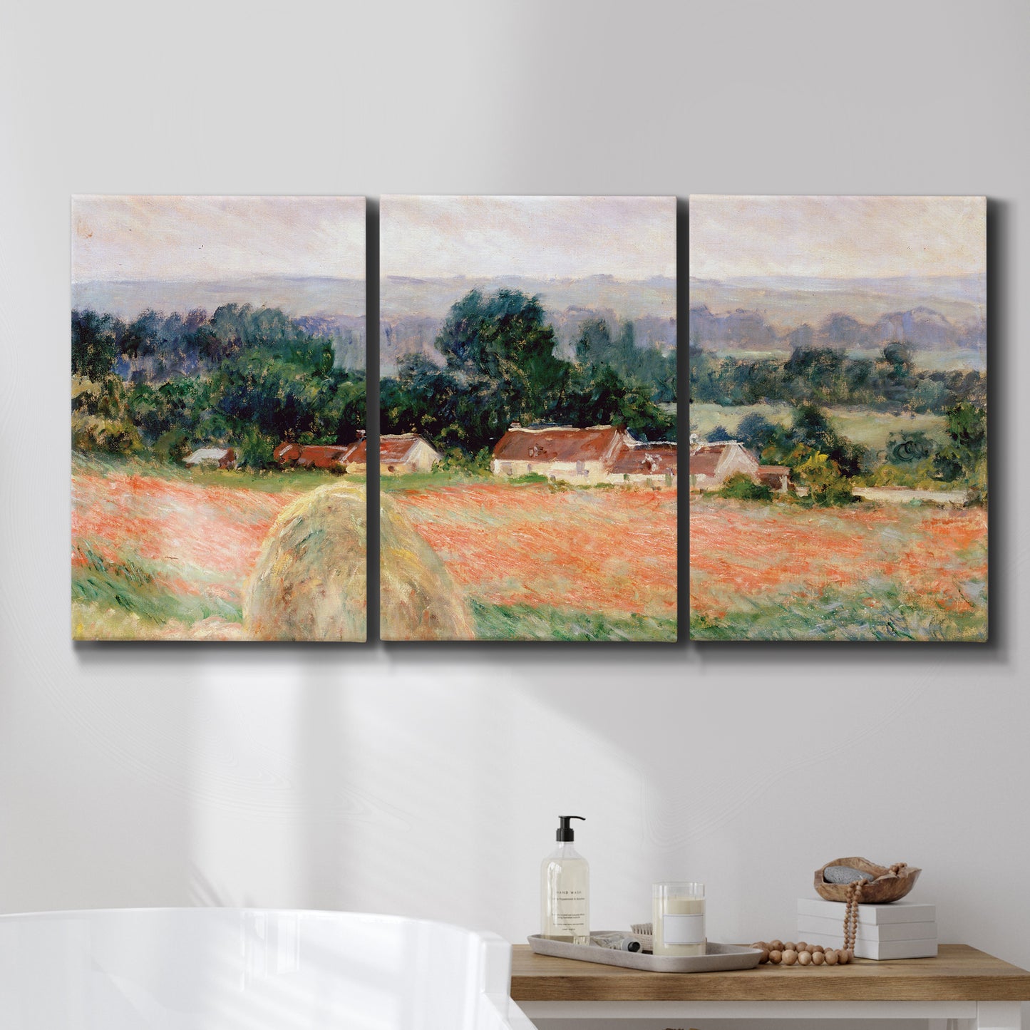 Three-panel canvas wall art featuring haystacks arranged in rural field, displayed in a bathroom above a bathtub.