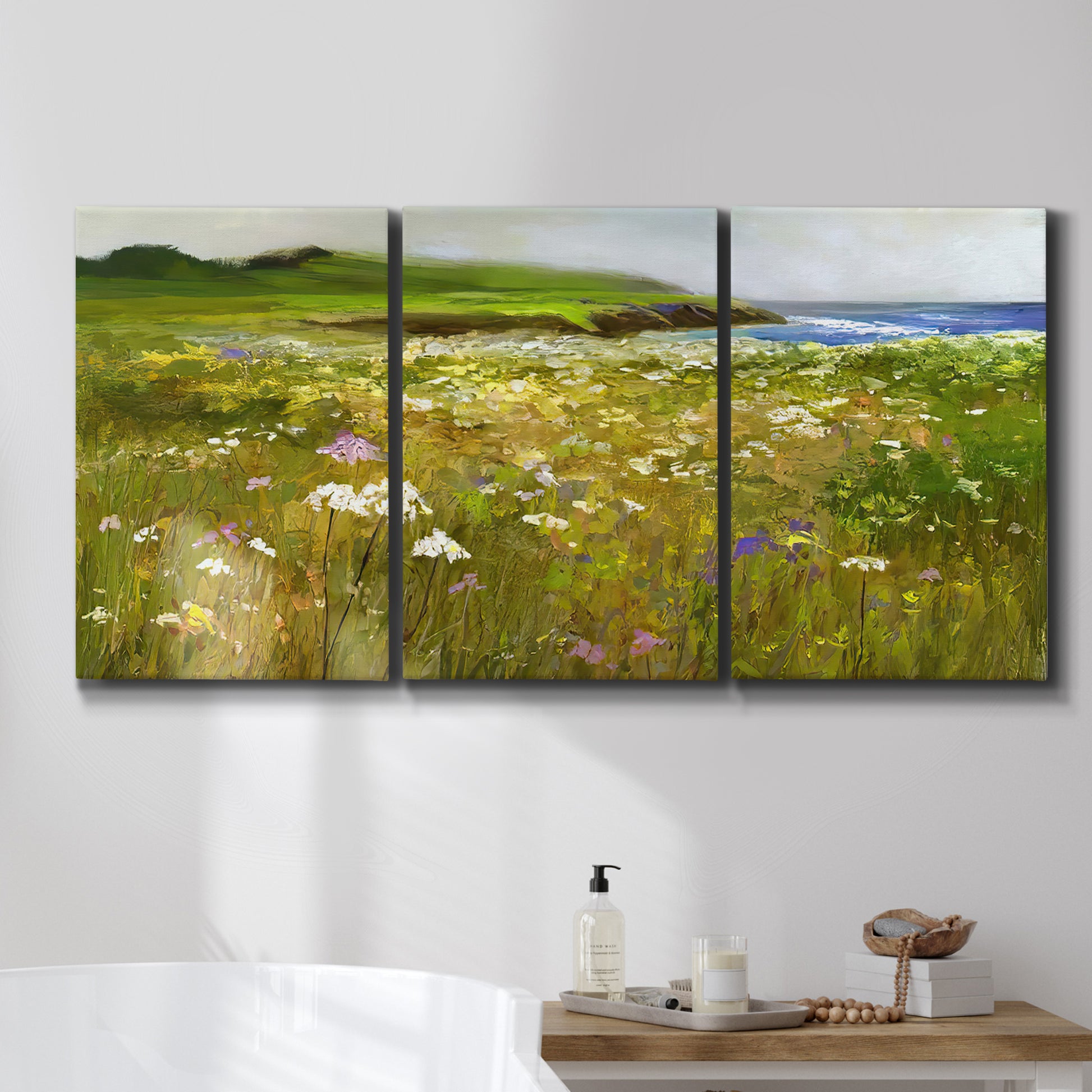 Three-panel canvas wall art featuring rugged coastal cliff landscape, displayed in a bathroom above a bathtub.