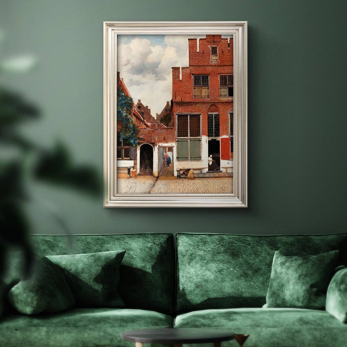 Realist city street scene by Johannes Vermeer in an ornate champagne frame displayed in a dark-toned interior setting.