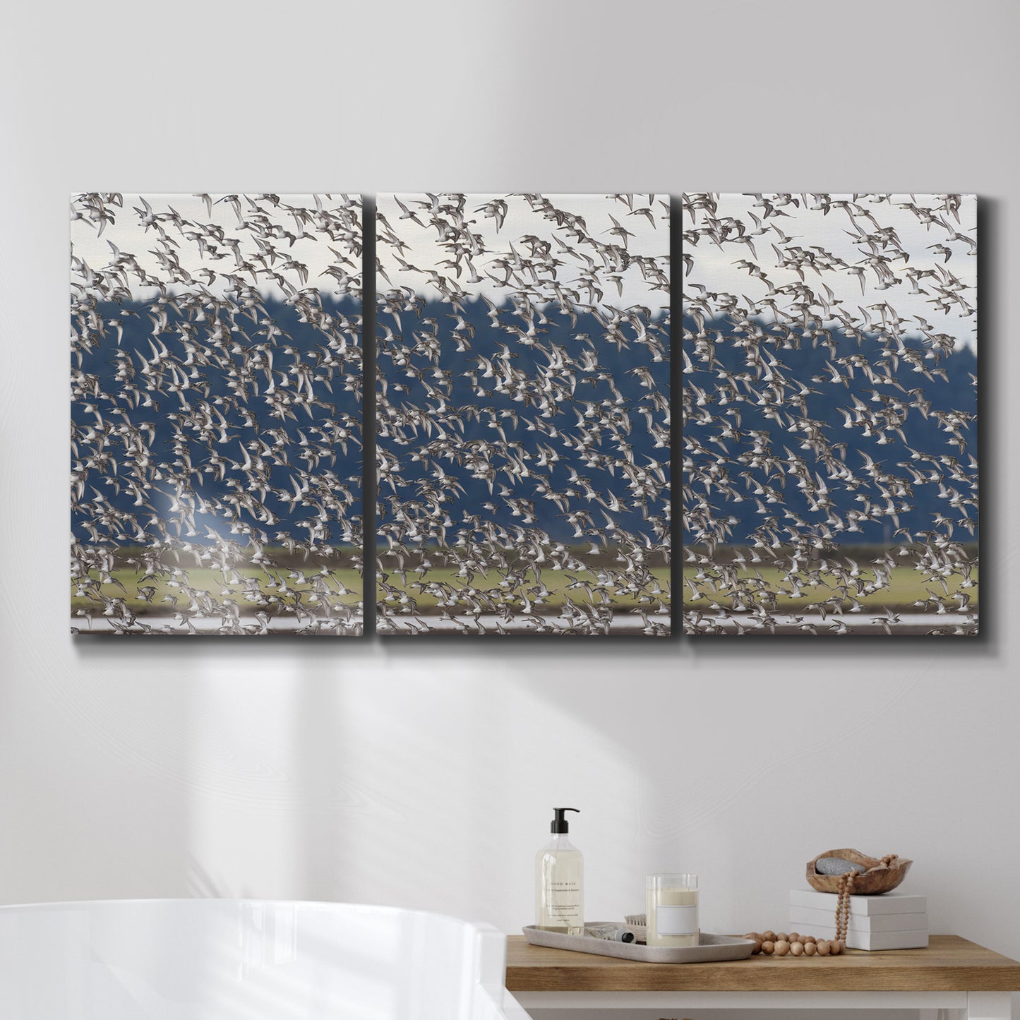 Three-panel canvas wall art featuring group of animals in open field, displayed in a bathroom above a bathtub.