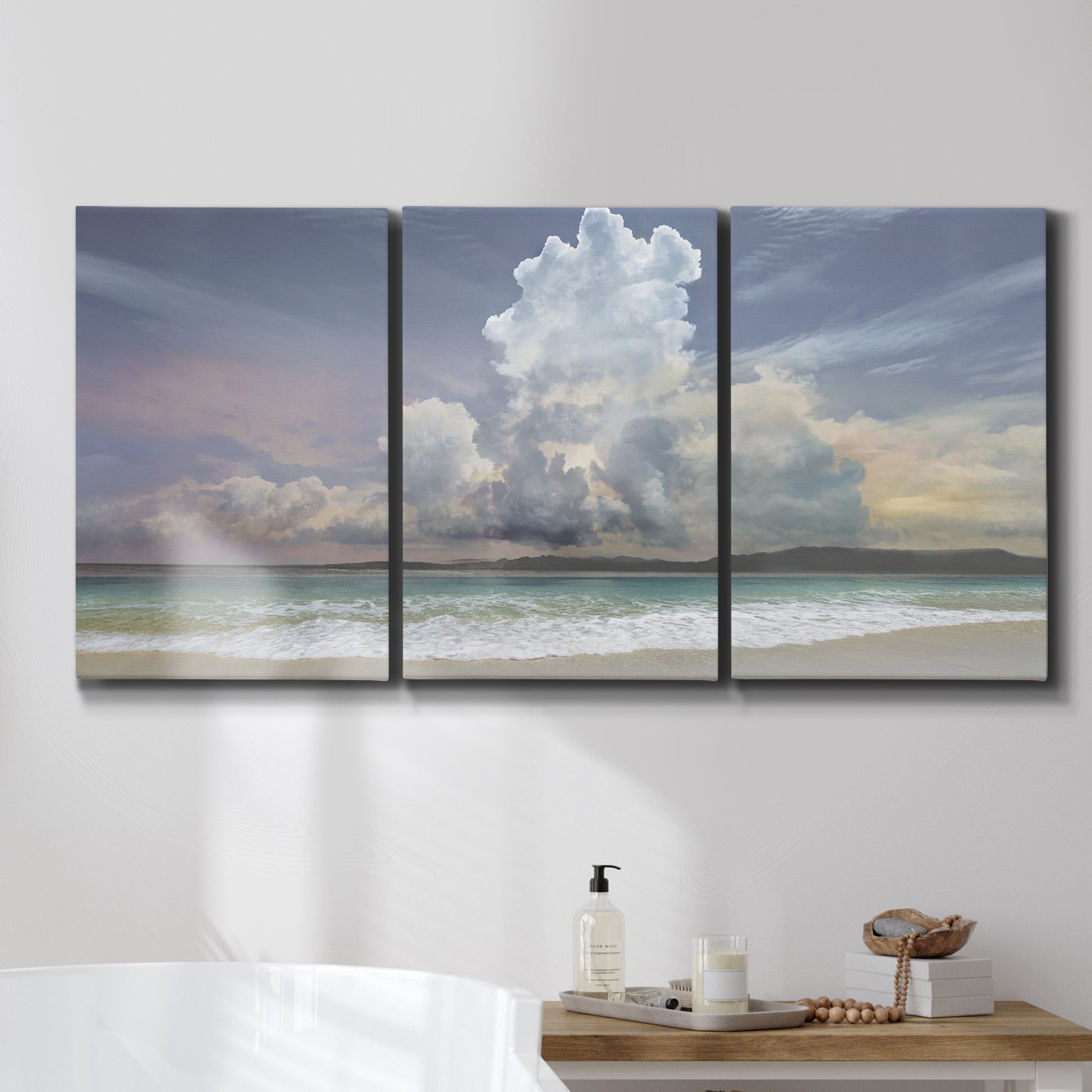 Three-panel canvas wall art featuring rain falling on sandy beach, displayed in a bathroom above a bathtub.
