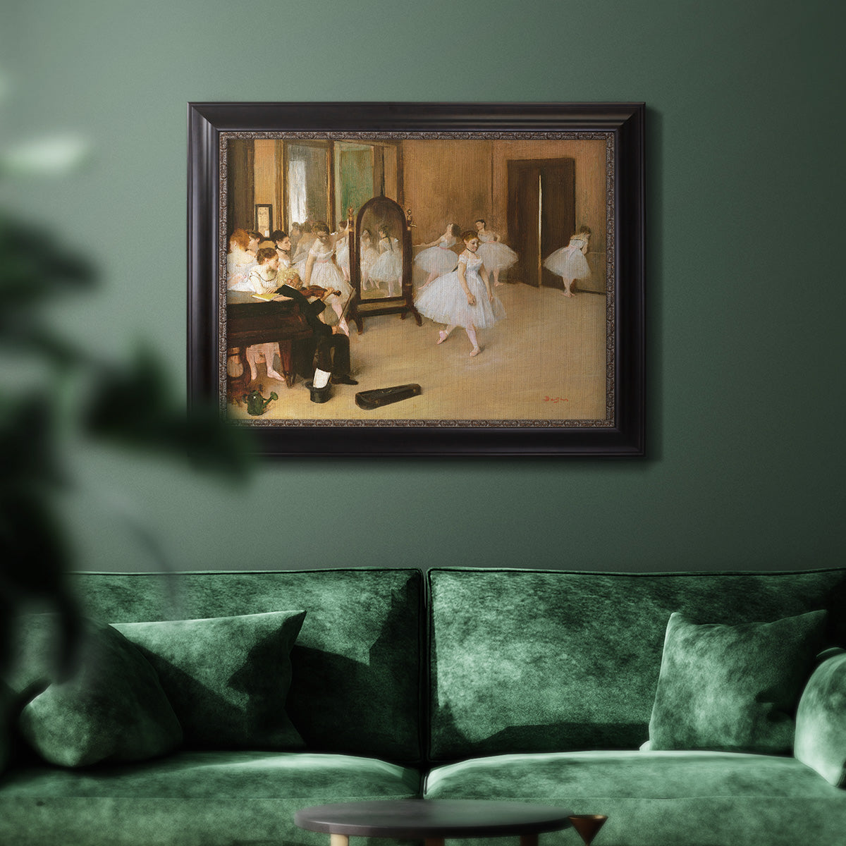 Impressionist dance class interior scene by Edgar Degas in an ornate black frame with gilded inner detail displayed in a dark-toned interior setting.