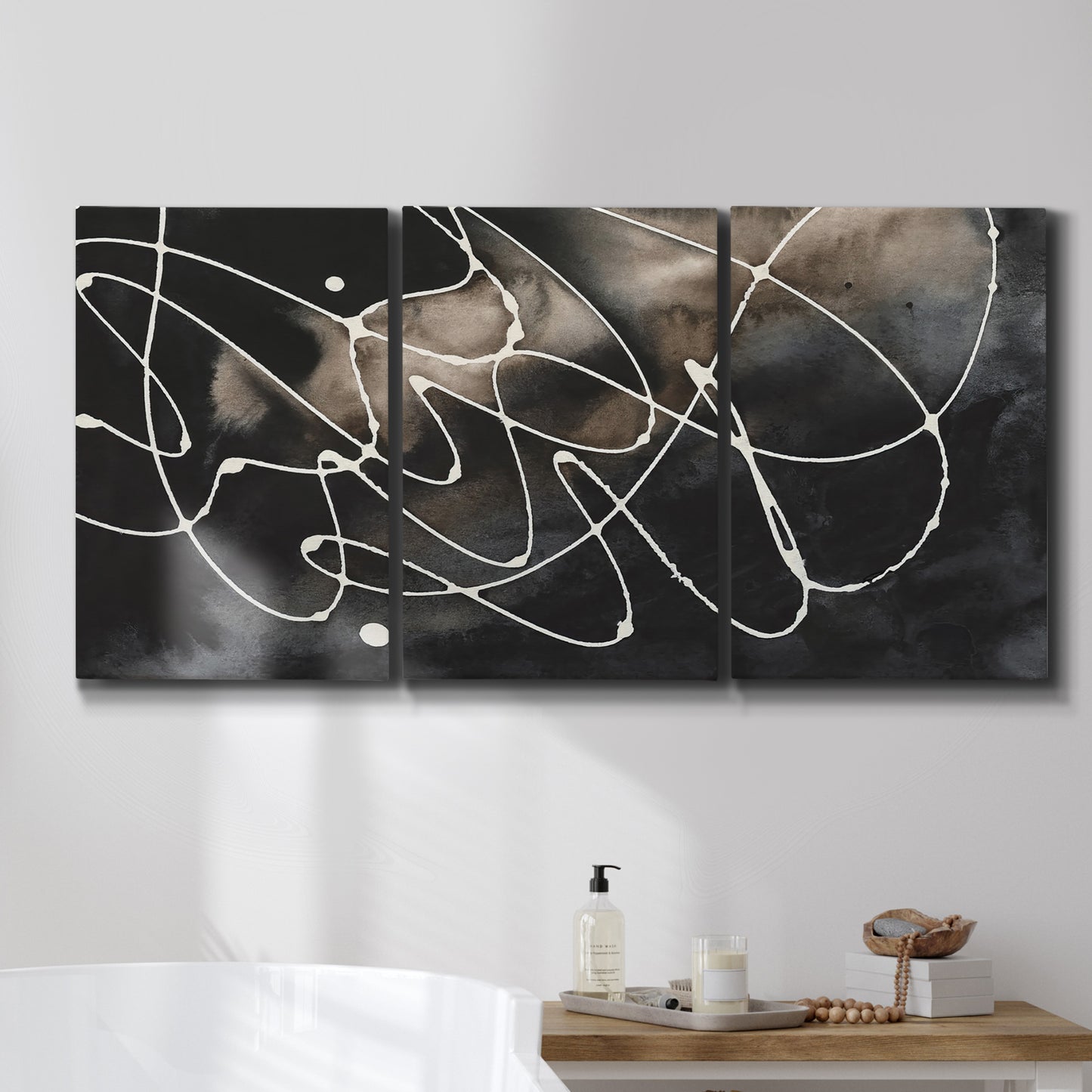 Three-panel canvas wall art featuring dark swirling abstract motion, displayed in a bathroom above a bathtub.