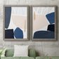 Set of two gray barnwood framed canvas prints depicting a coordinated art pair of large navy cream and beige organic geometric shapes rendered as minimalist color-block abstracts above a sofa in a modern living room.