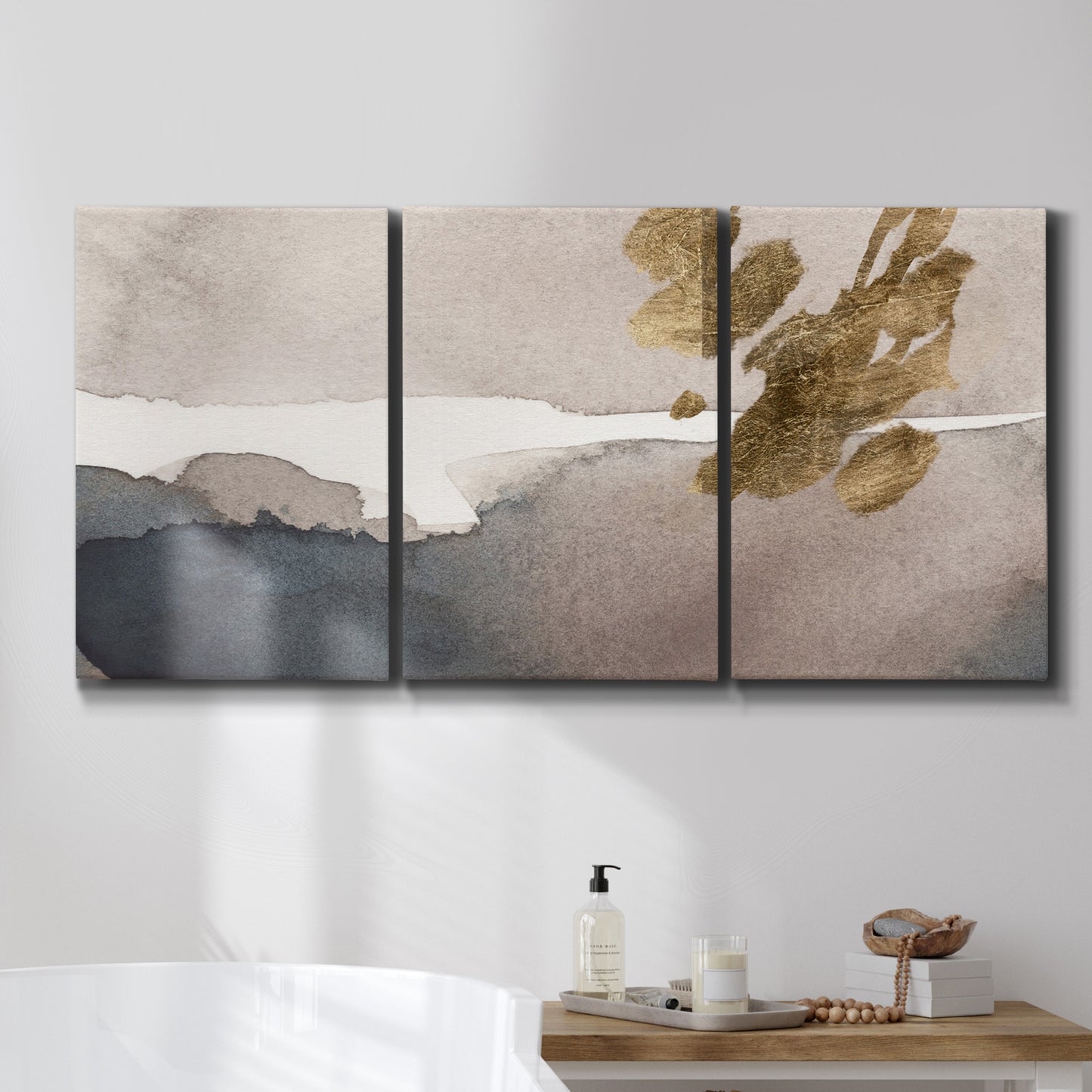 Three-panel canvas wall art featuring abstract watercolor with gold accents, displayed in a bathroom above a bathtub.