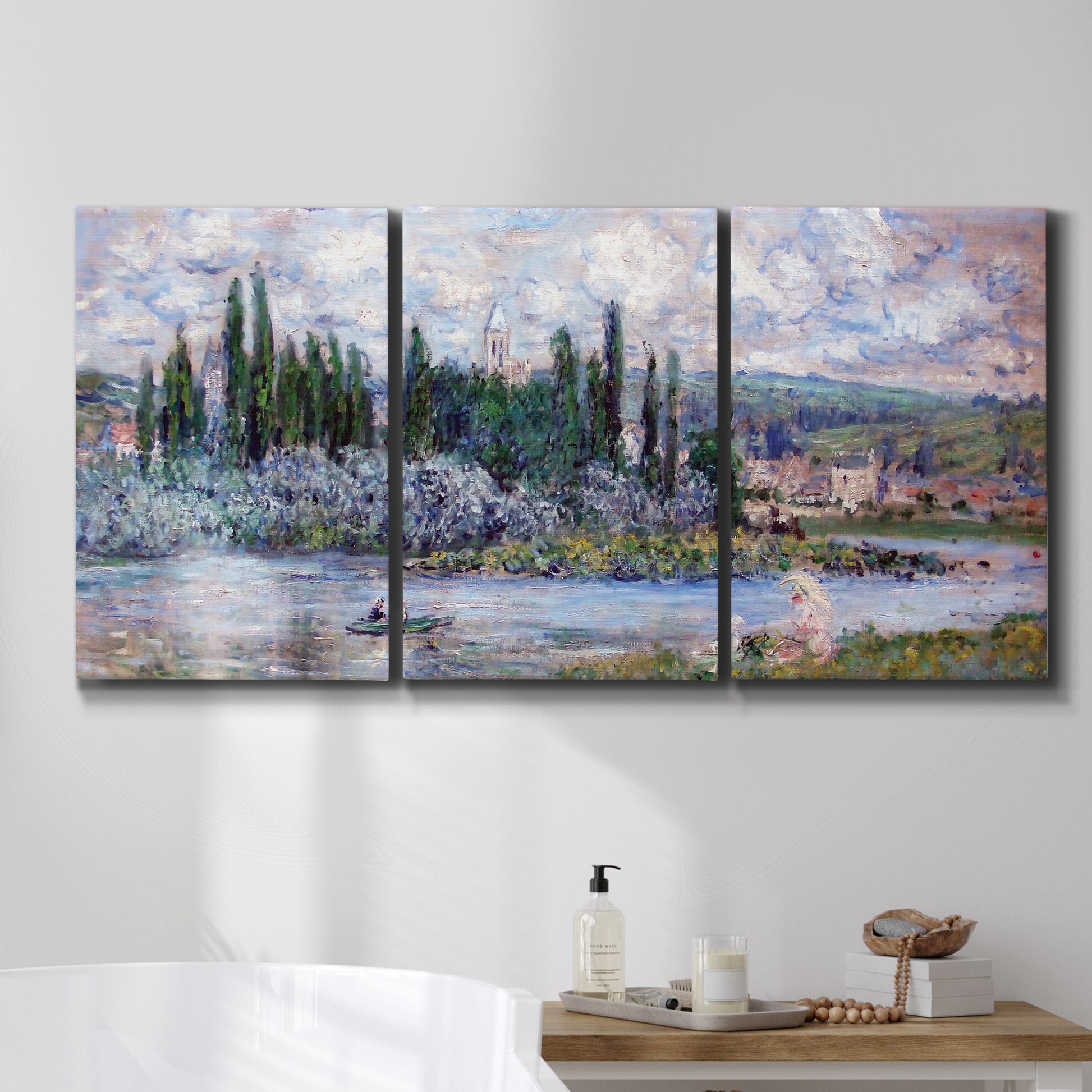 Three-panel canvas wall art featuring summer village view along river, displayed in a bathroom above a bathtub.