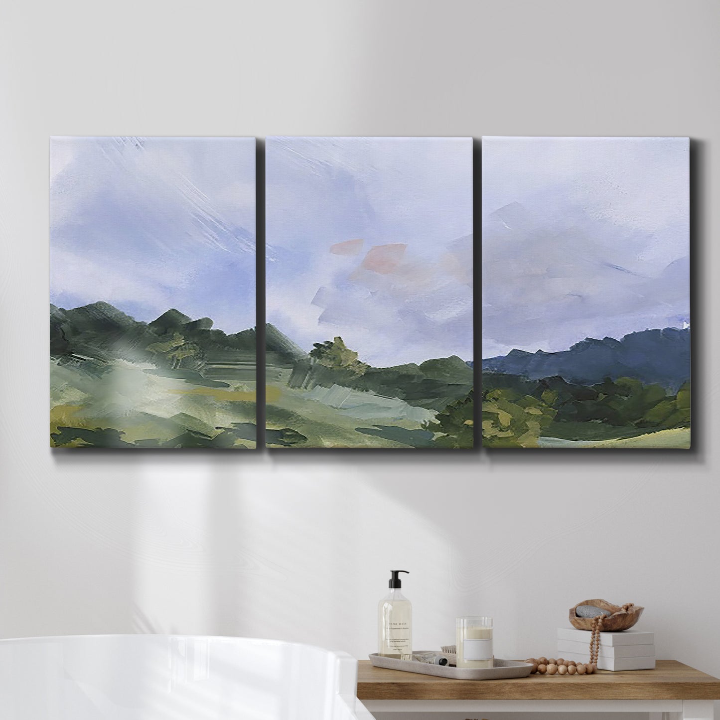 Three-panel canvas wall art featuring wide open pastoral horizon landscape, displayed in a bathroom above a bathtub.