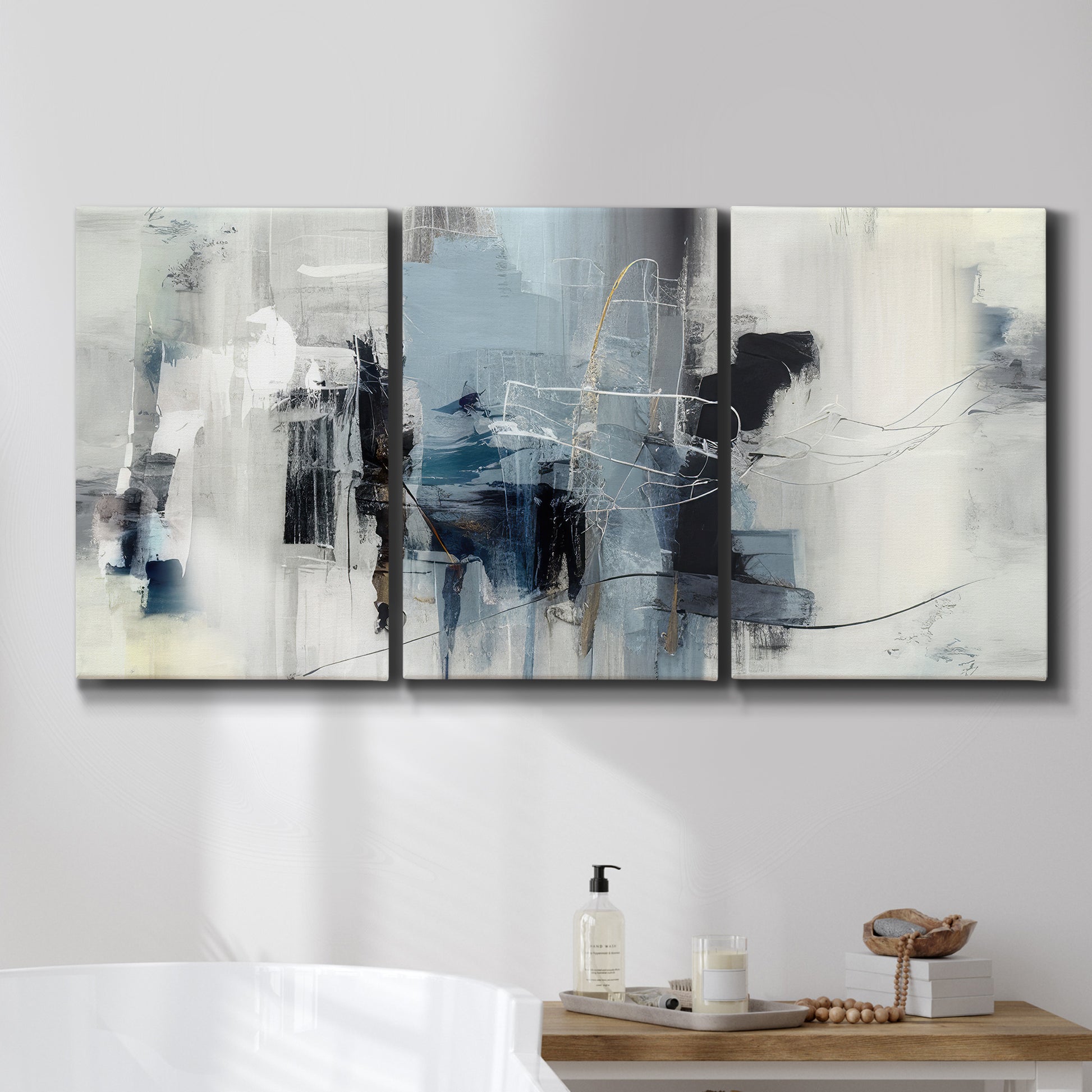 Three-panel canvas wall art featuring cool abstract winter color wash, displayed in a bathroom above a bathtub.