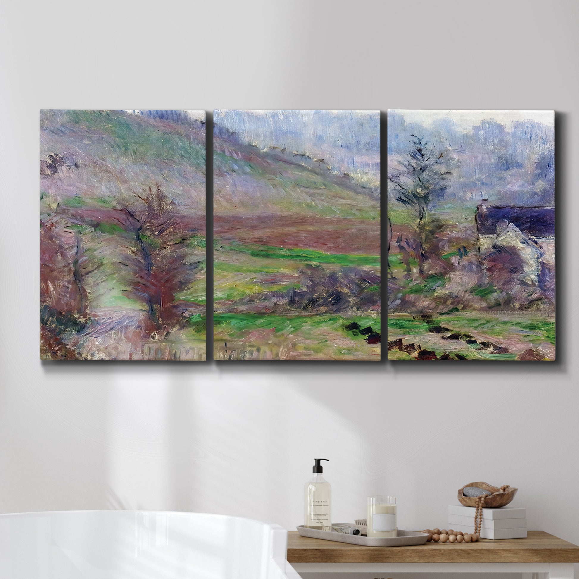 Three-panel canvas wall art featuring cliffside cottage overlooking sea, displayed in a bathroom above a bathtub.