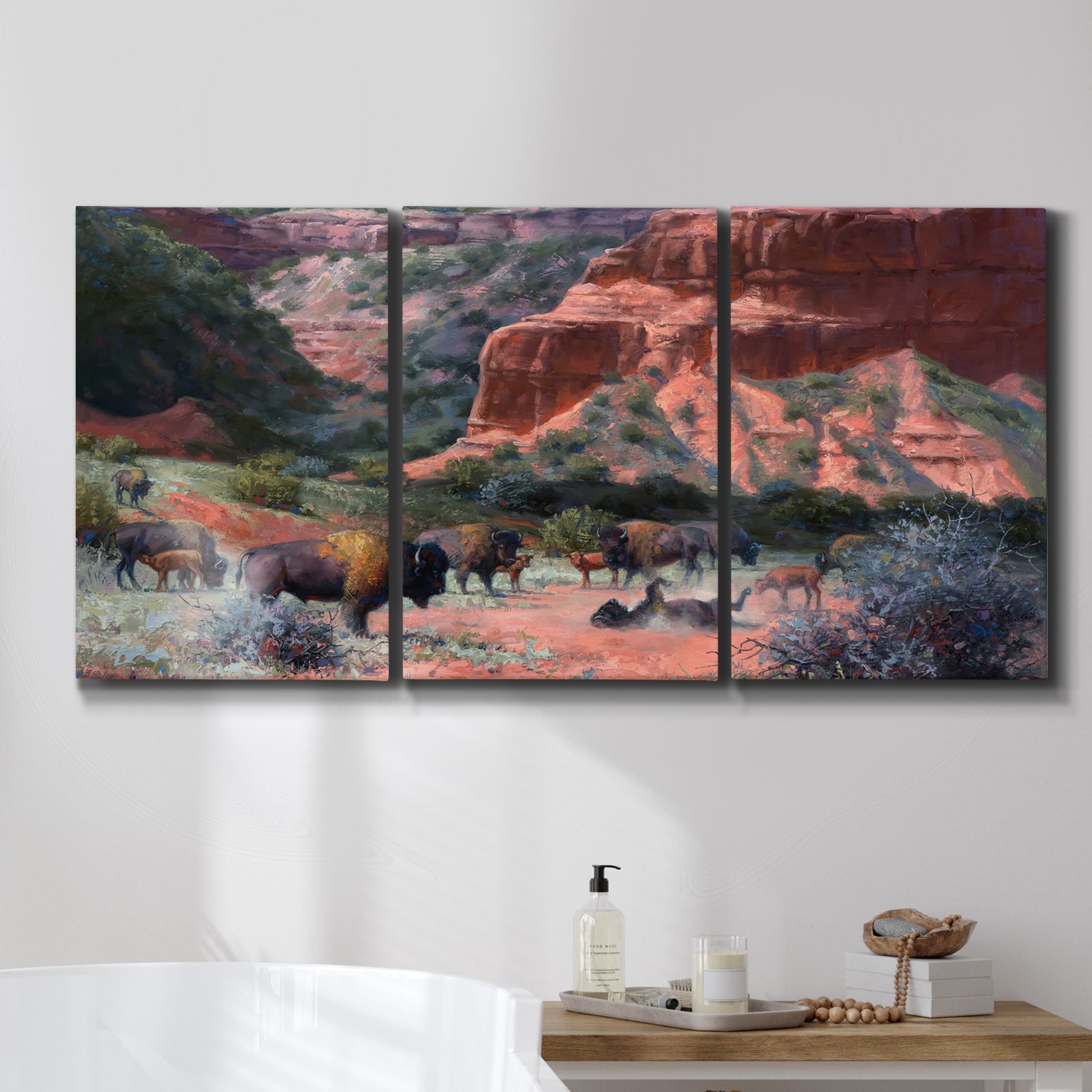 Three-panel canvas wall art featuring rugged canyon landscape with wildlife, displayed in a bathroom above a bathtub.