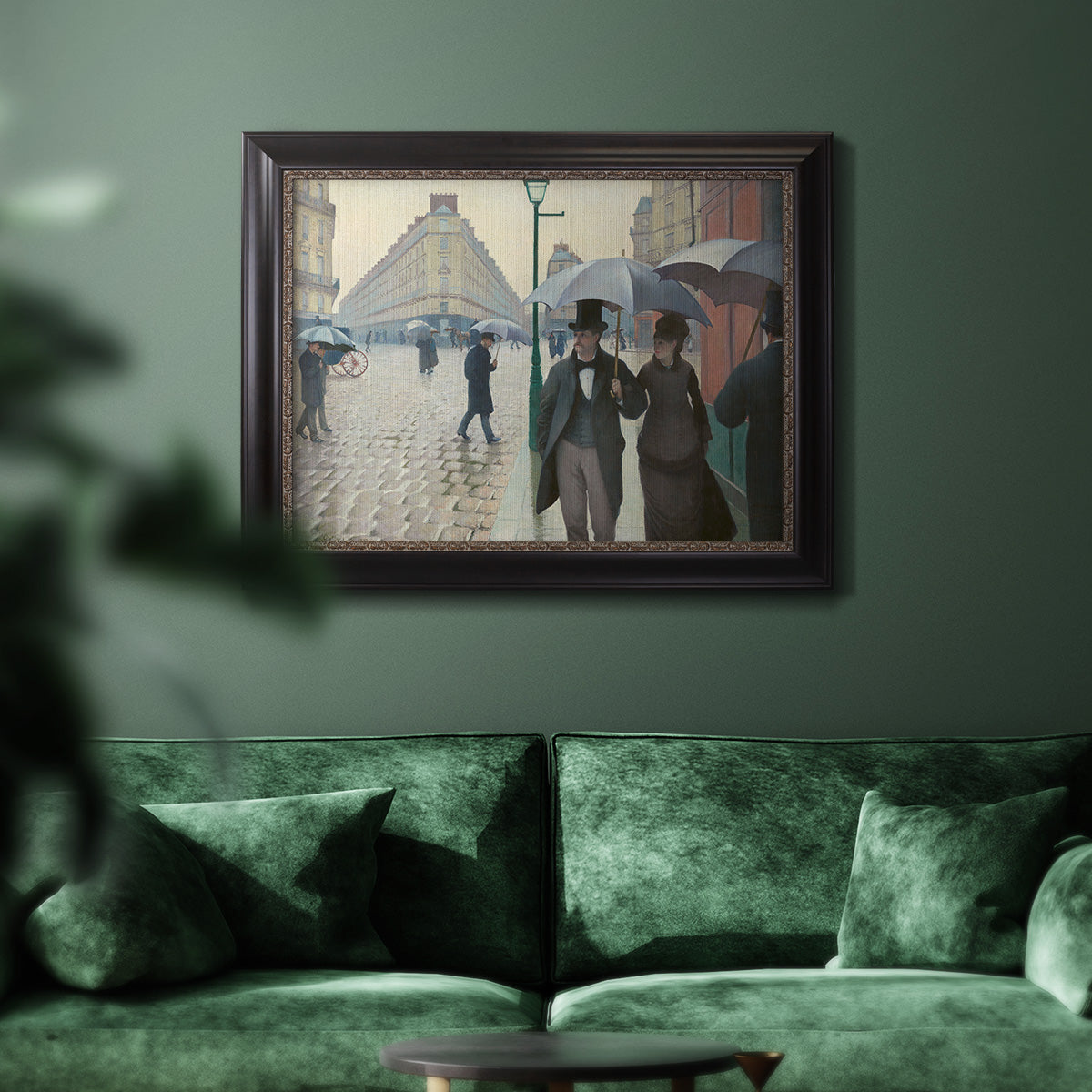 Impressionist urban street scene in the rain by Gustave Caillebotte in an ornate black frame with gilded inner detail displayed in a dark-toned interior setting.