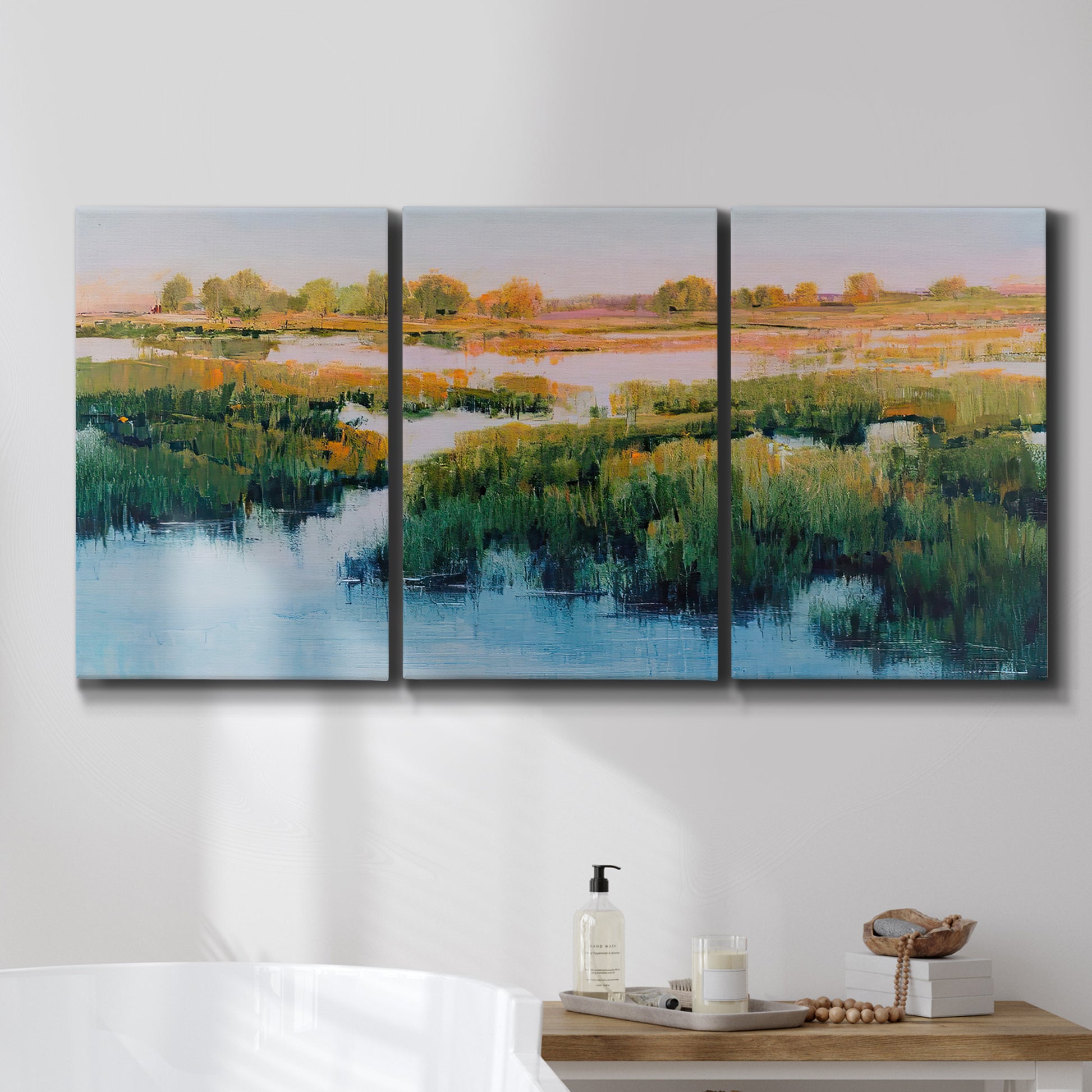 Three-panel canvas wall art featuring pastoral marshland landscape, displayed in a bathroom above a bathtub.