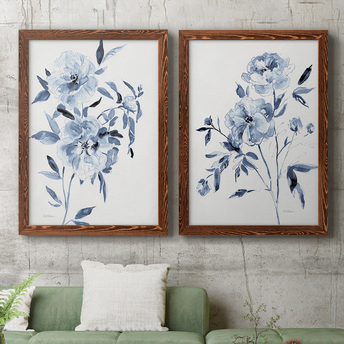 Set of two maple barnwood framed canvas prints depicting a coordinated art pair of loose blue flowers and leafy branches rendered as expressive watercolor botanical paintings above a sofa in a modern living room.
