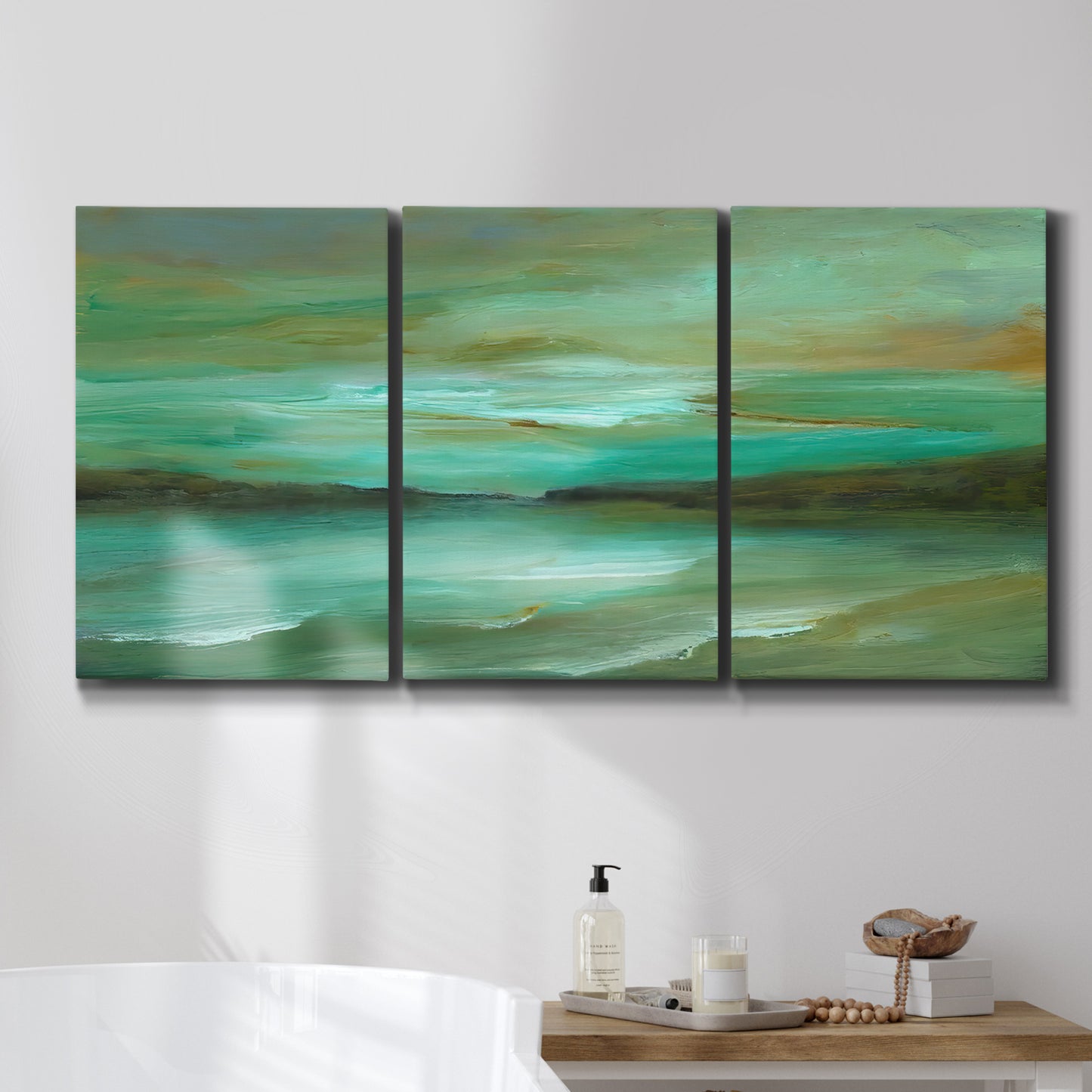 Three-panel canvas wall art featuring hidden coastal cove landscape, displayed in a bathroom above a bathtub.