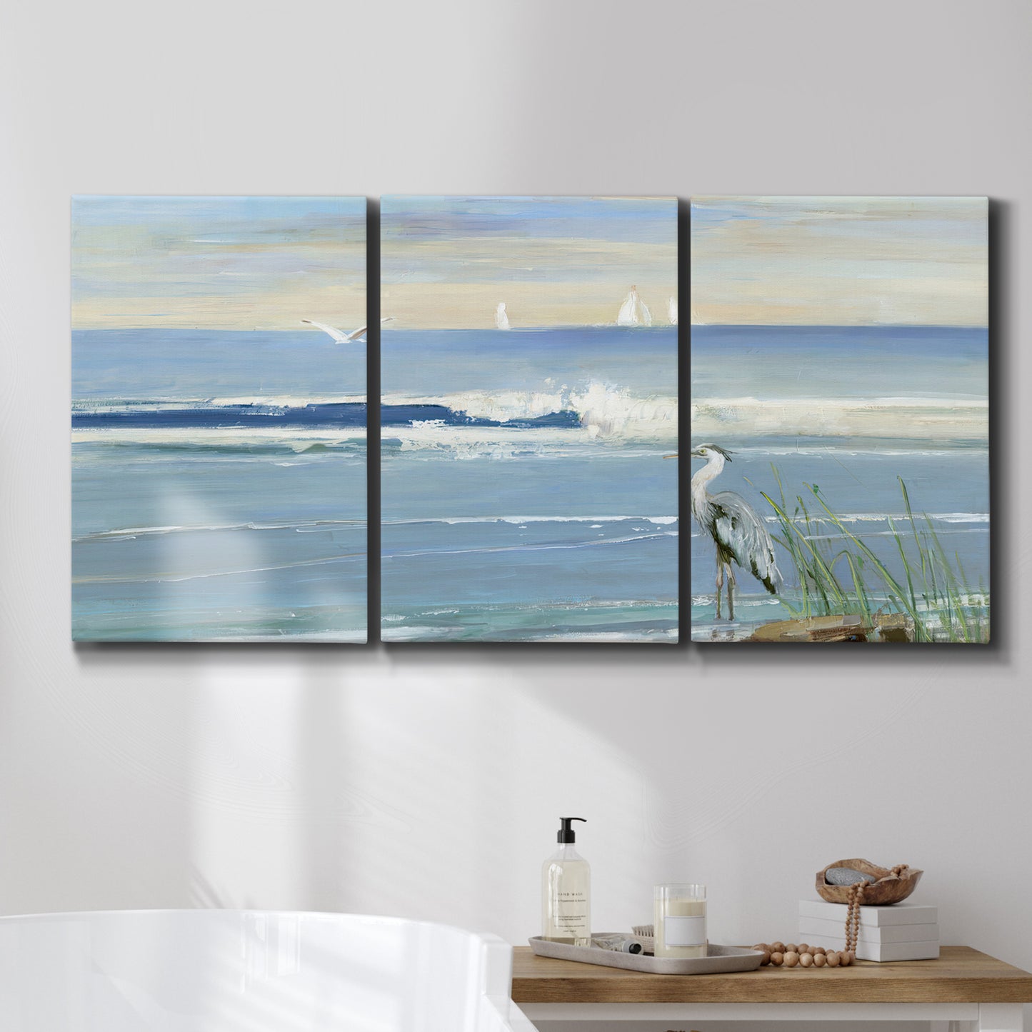 Three-panel canvas wall art featuring sunrise reflecting across bay waters, displayed in a bathroom above a bathtub.