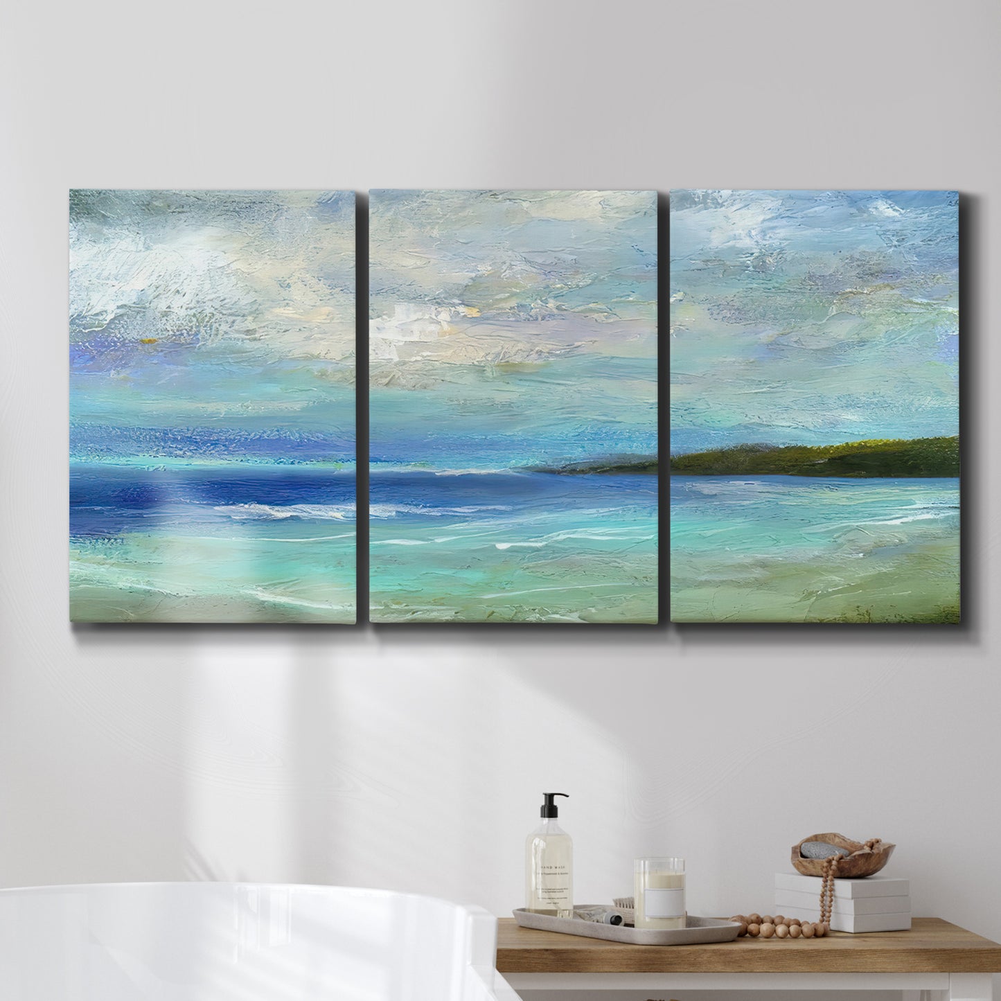 Three-panel canvas wall art featuring narrow island inlet waters, displayed in a bathroom above a bathtub.