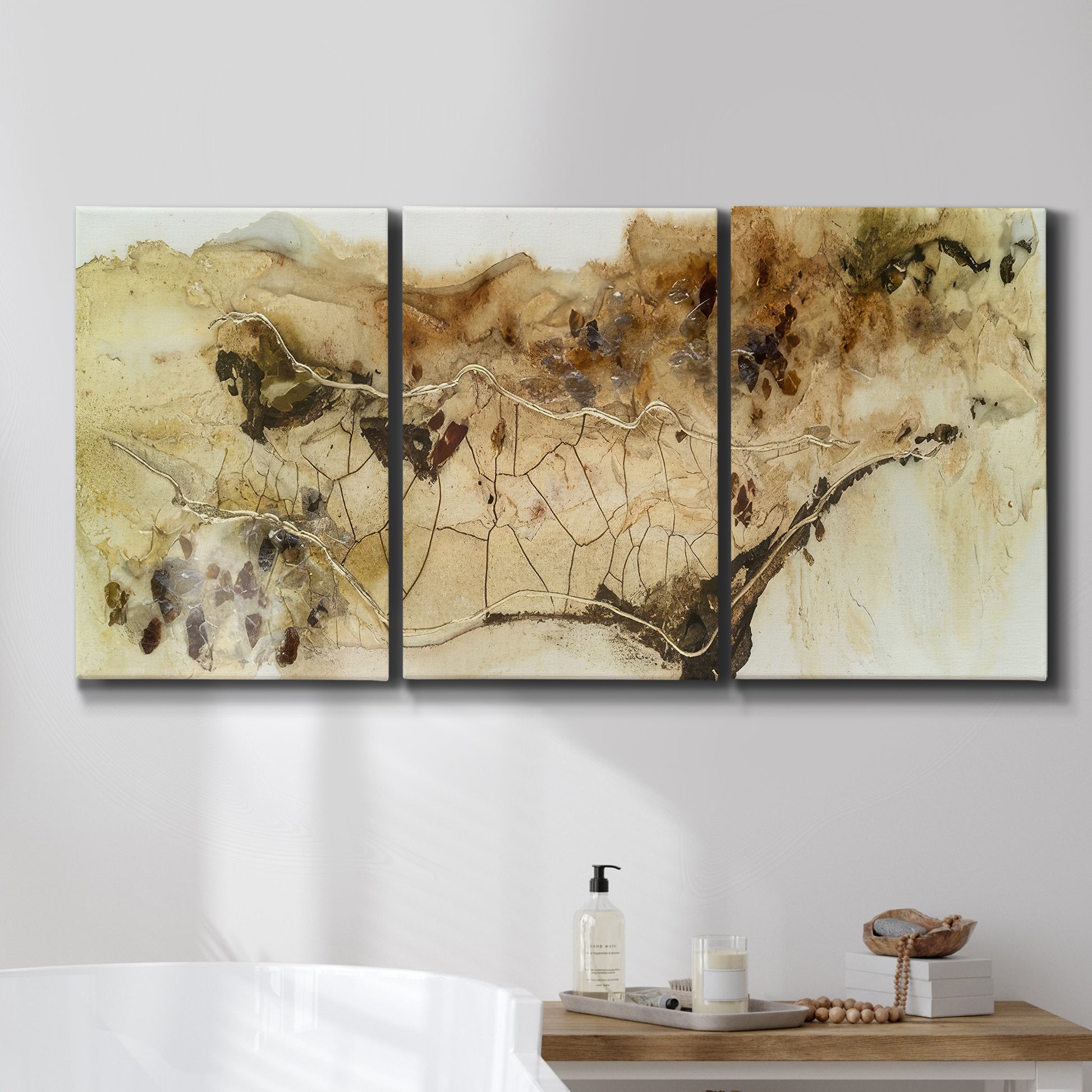 Three-panel canvas wall art featuring muted abstract with metallic gold accents, displayed in a bathroom above a bathtub.