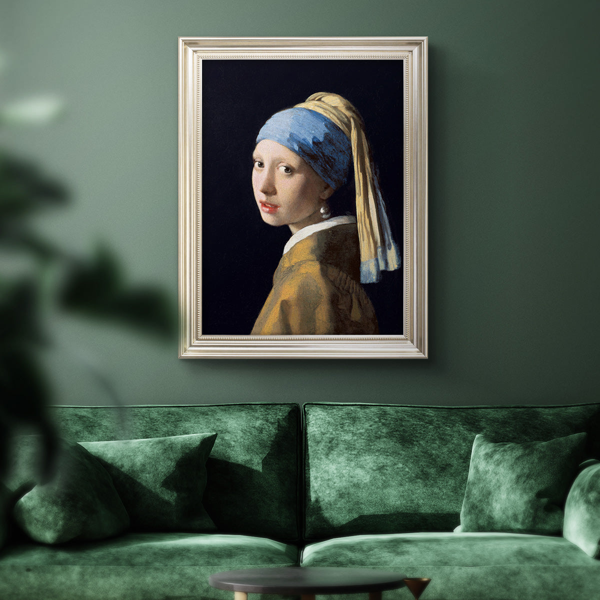 Iconic portrait of a girl wearing a pearl earring by Johannes Vermeer in an ornate champagne frame displayed in a dark-toned interior setting.