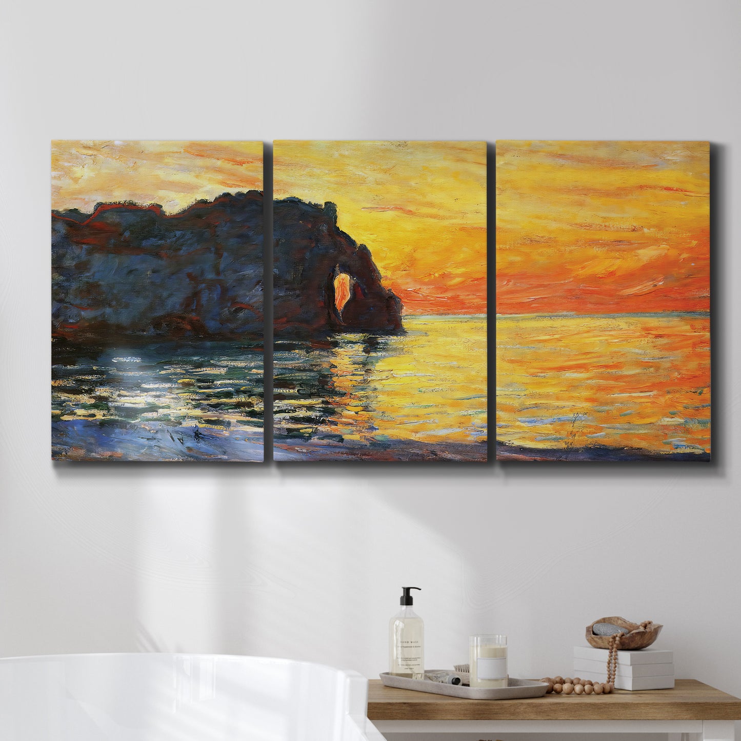 Three-panel canvas wall art featuring arched coastal cliff above sea, displayed in a bathroom above a bathtub.