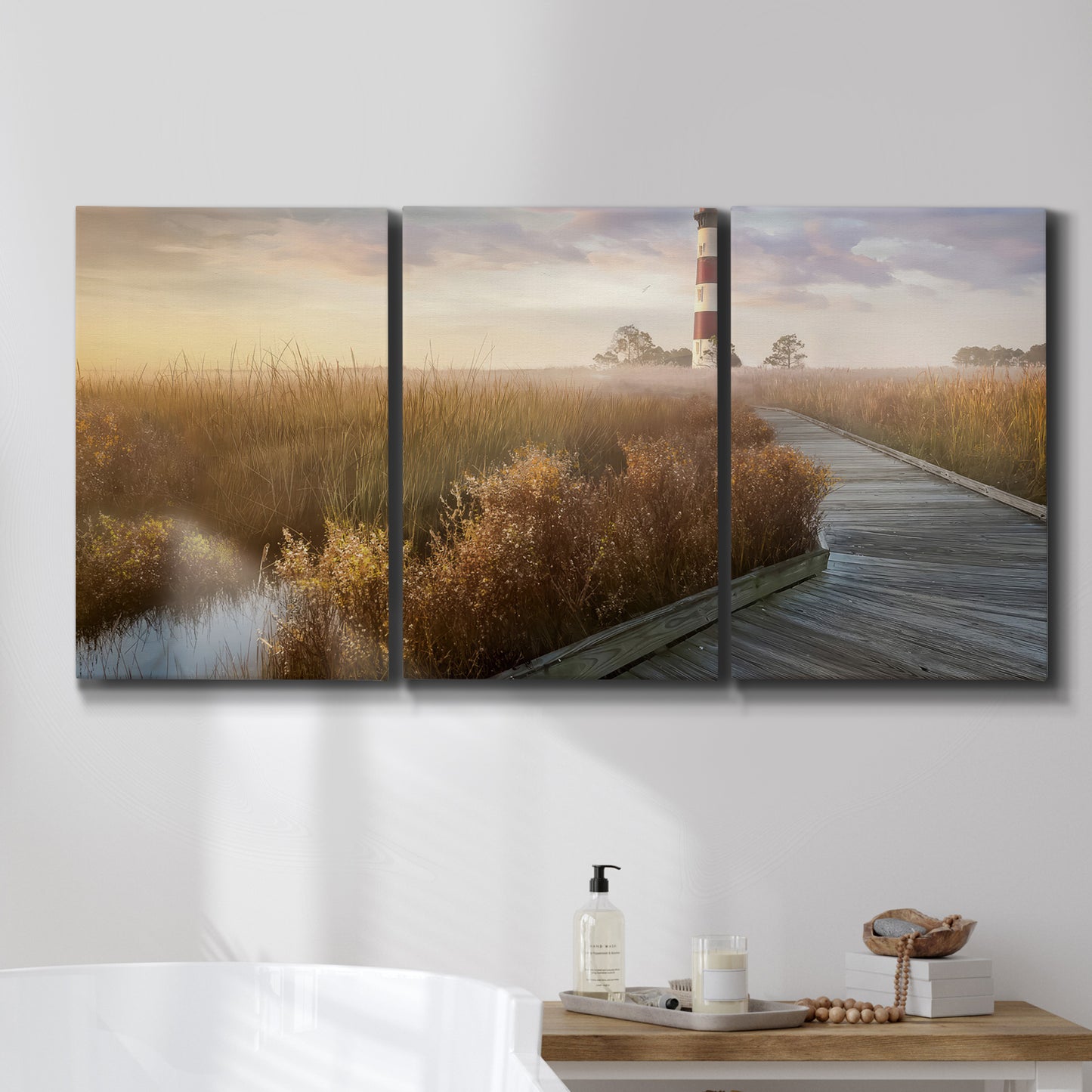 Three-panel canvas wall art featuring coastal path leading to shore, displayed in a bathroom above a bathtub.