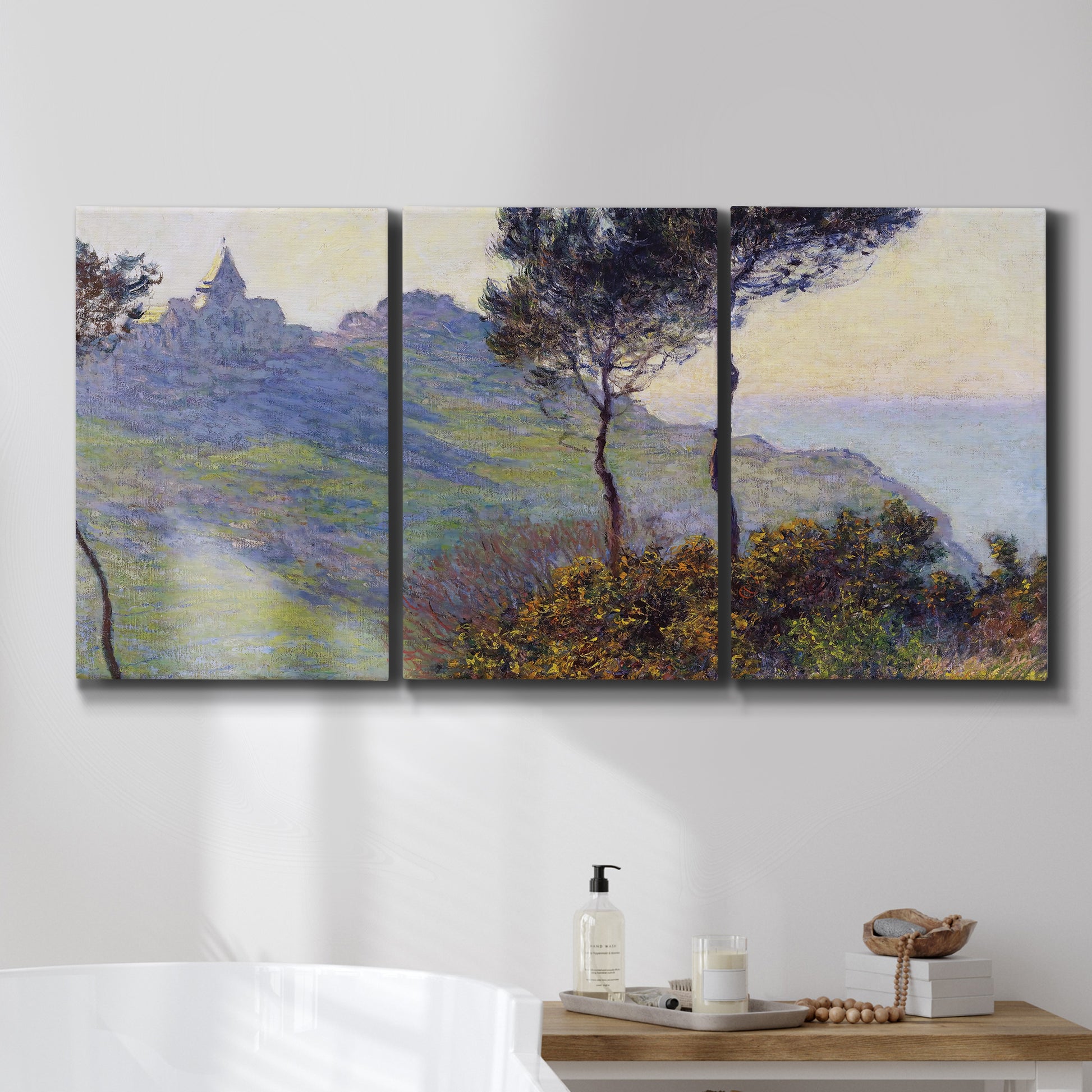 Three-panel canvas wall art featuring village church at sunset, displayed in a bathroom above a bathtub.