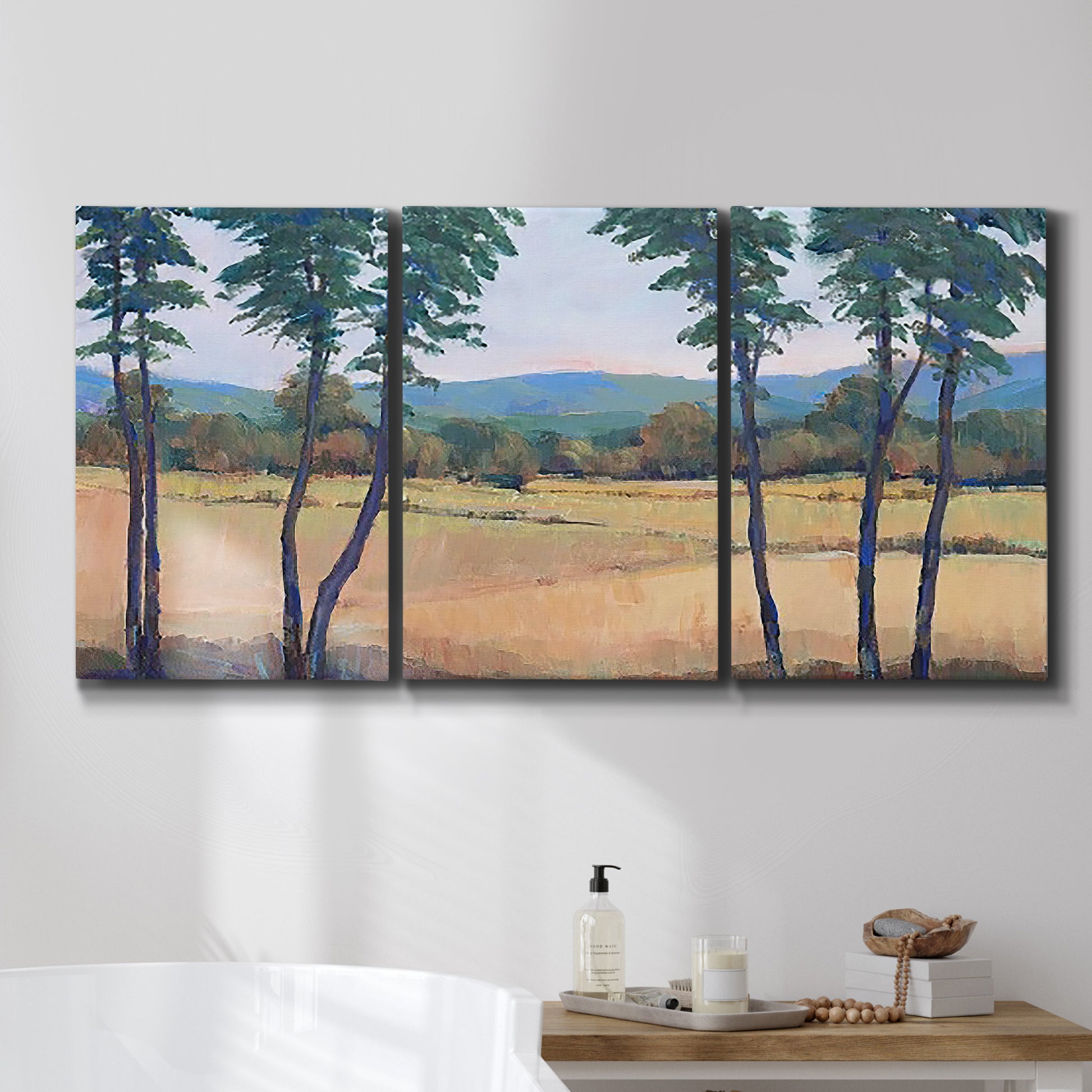 Three-panel canvas wall art featuring quiet morning landscape with trees, displayed in a bathroom above a bathtub.