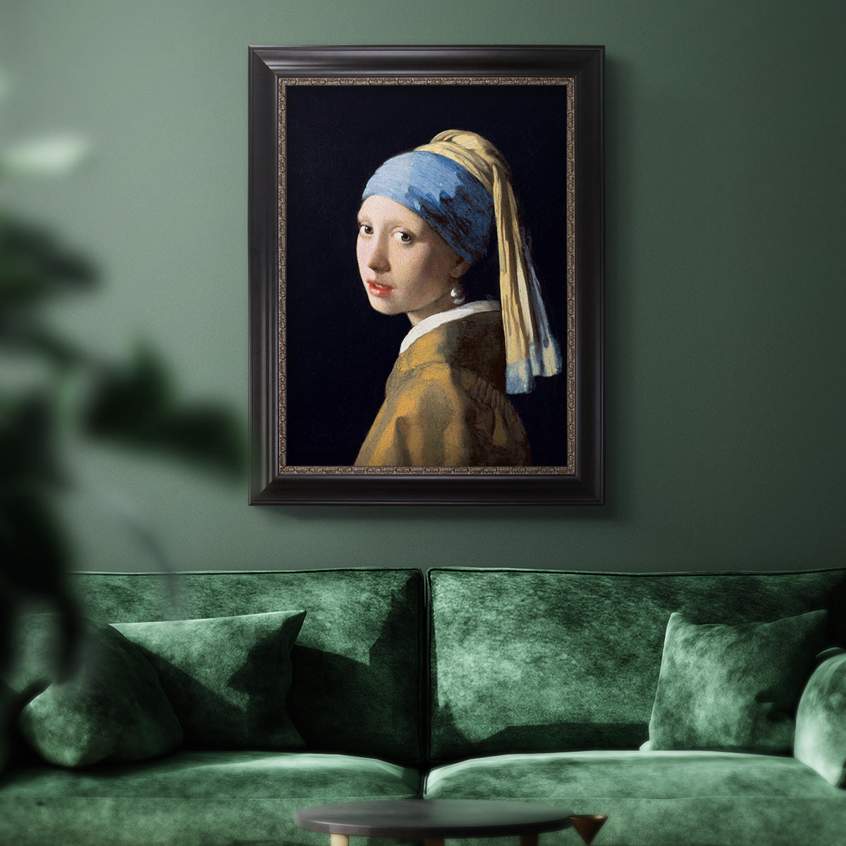 Iconic portrait of a girl wearing a pearl earring by Johannes Vermeer in an ornate black frame with gilded inner detail displayed in a dark-toned interior setting.
