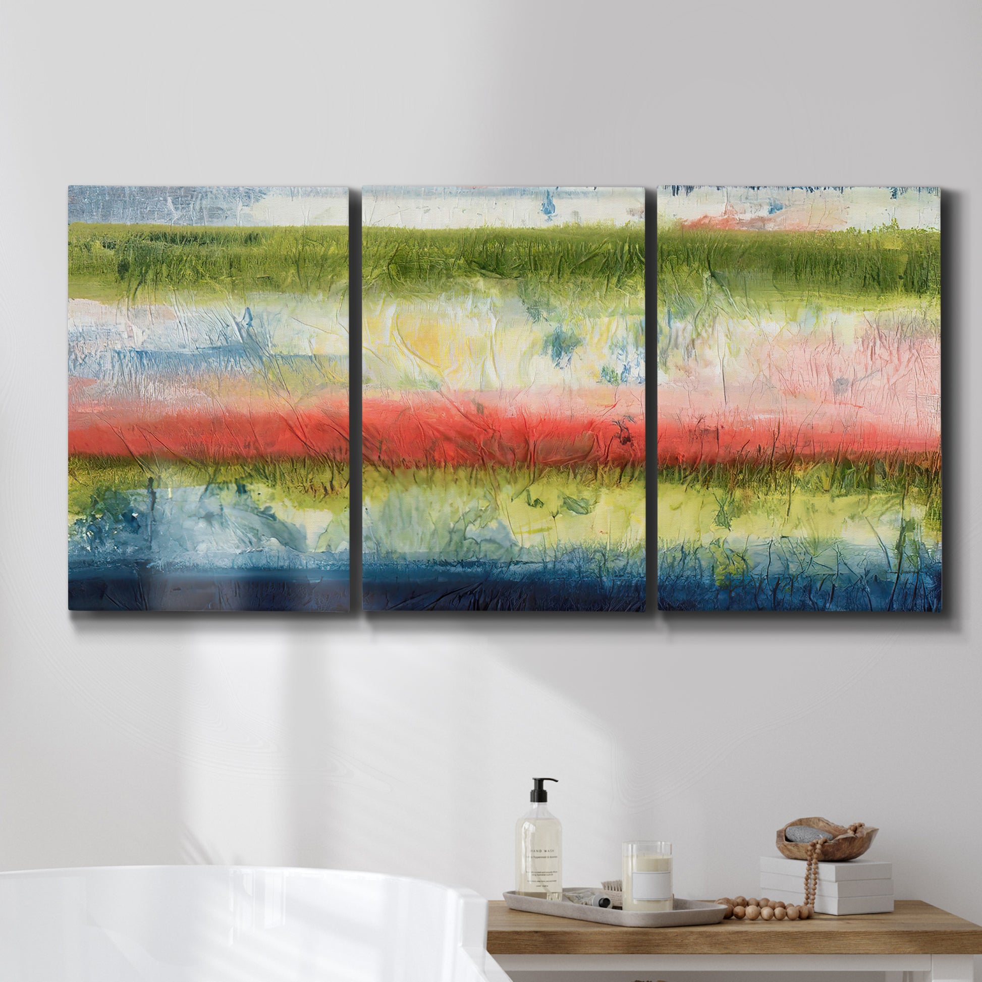 Three-panel canvas wall art featuring layered abstract color banding, displayed in a bathroom above a bathtub.