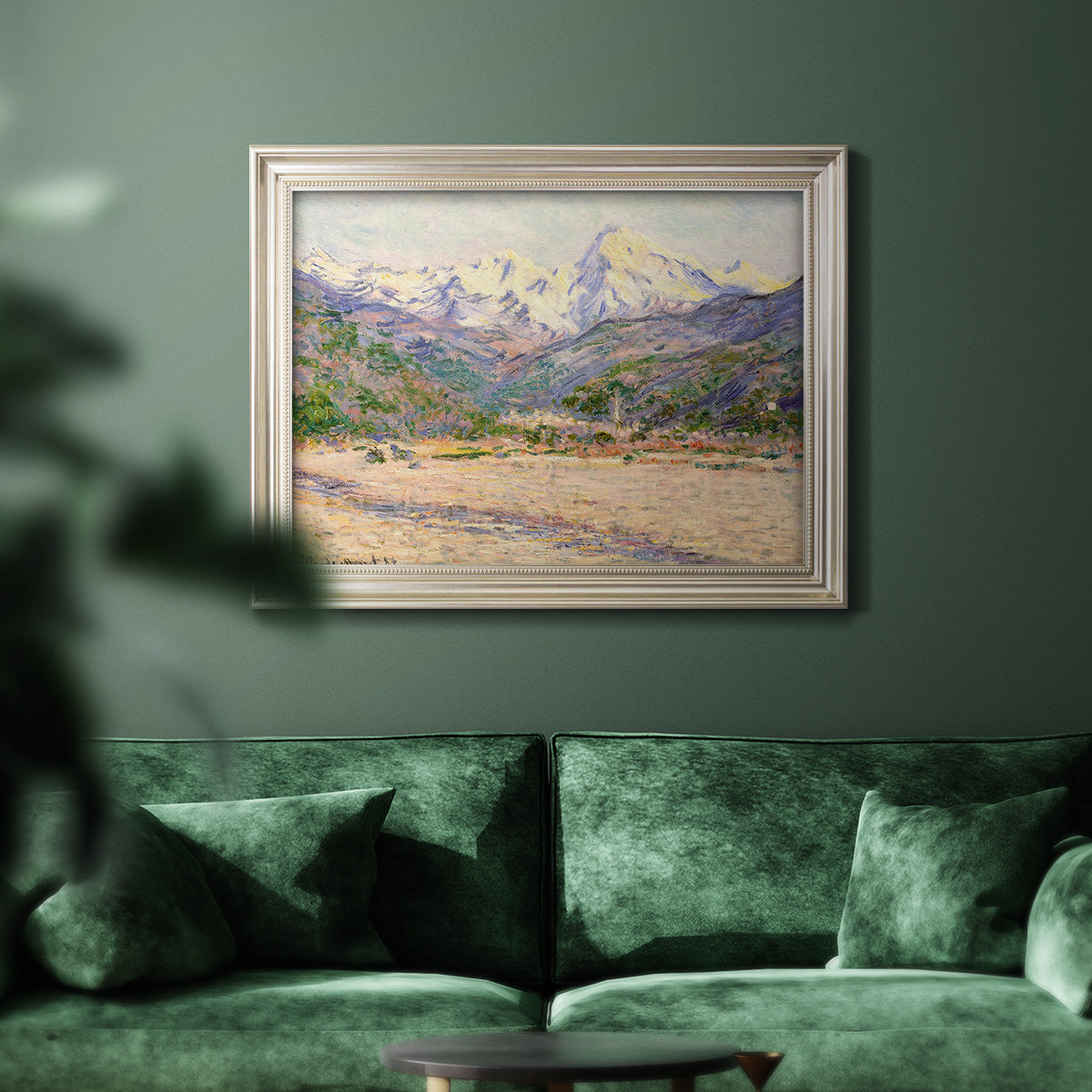 Impressionist valley landscape in southern France by Claude Monet in an ornate champagne frame displayed in a dark-toned interior setting.
