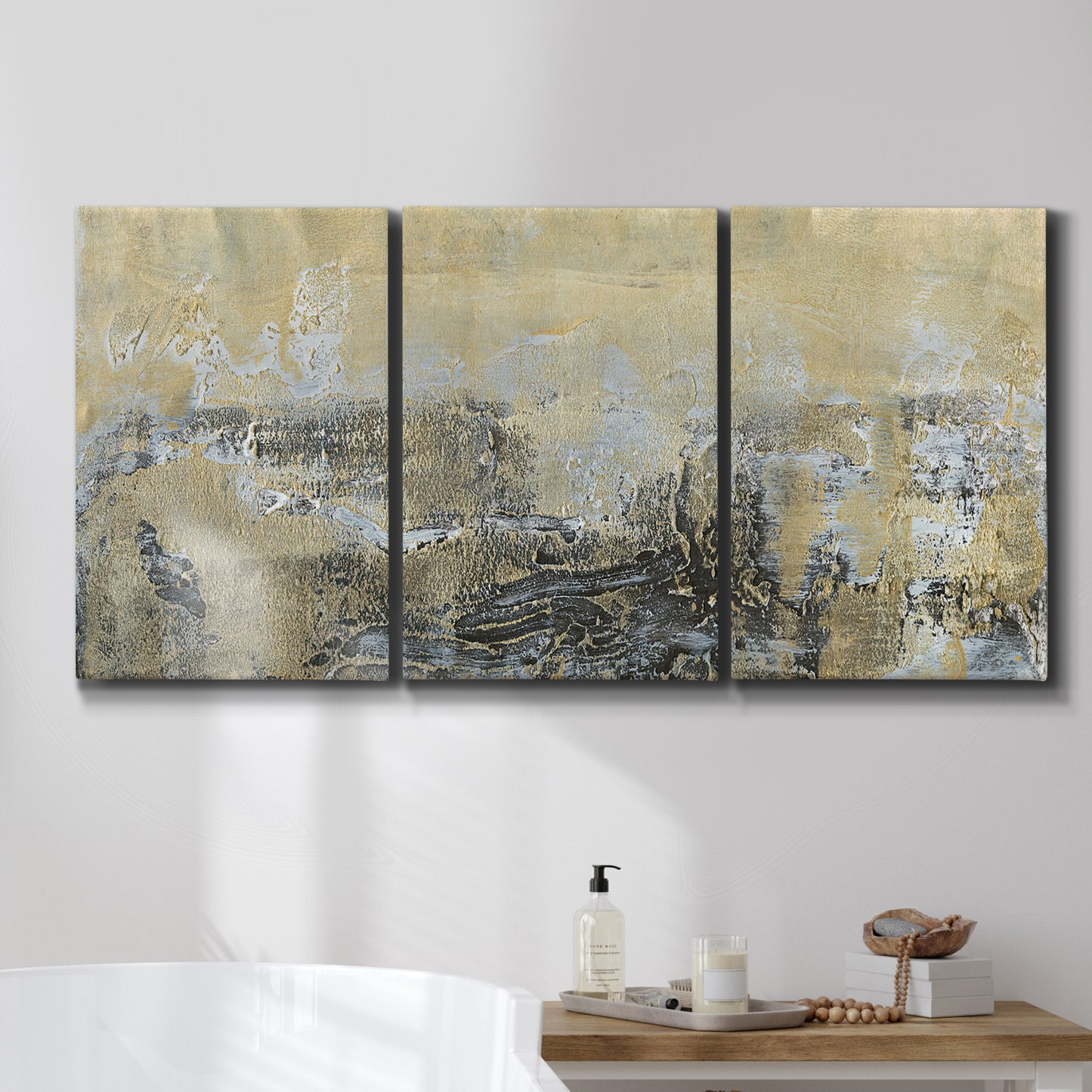 Three-panel canvas wall art featuring gold toned abstract horizon, displayed in a bathroom above a bathtub.