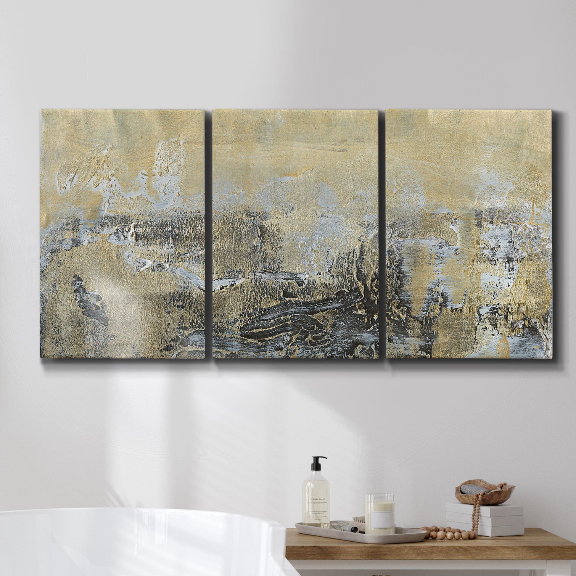 Three-panel canvas wall art featuring gold toned abstract horizon, displayed in a bathroom above a bathtub.