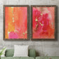 Set of two walnut barnwood framed canvas prints depicting a coordinated art pair of luminous coral orange and pink color fields with gold flecks rendered as glamorous fluid abstracts above a sofa in a modern living room.