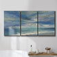 Three-panel canvas wall art featuring sunbeams breaking through coastal clouds, displayed in a bathroom above a bathtub.