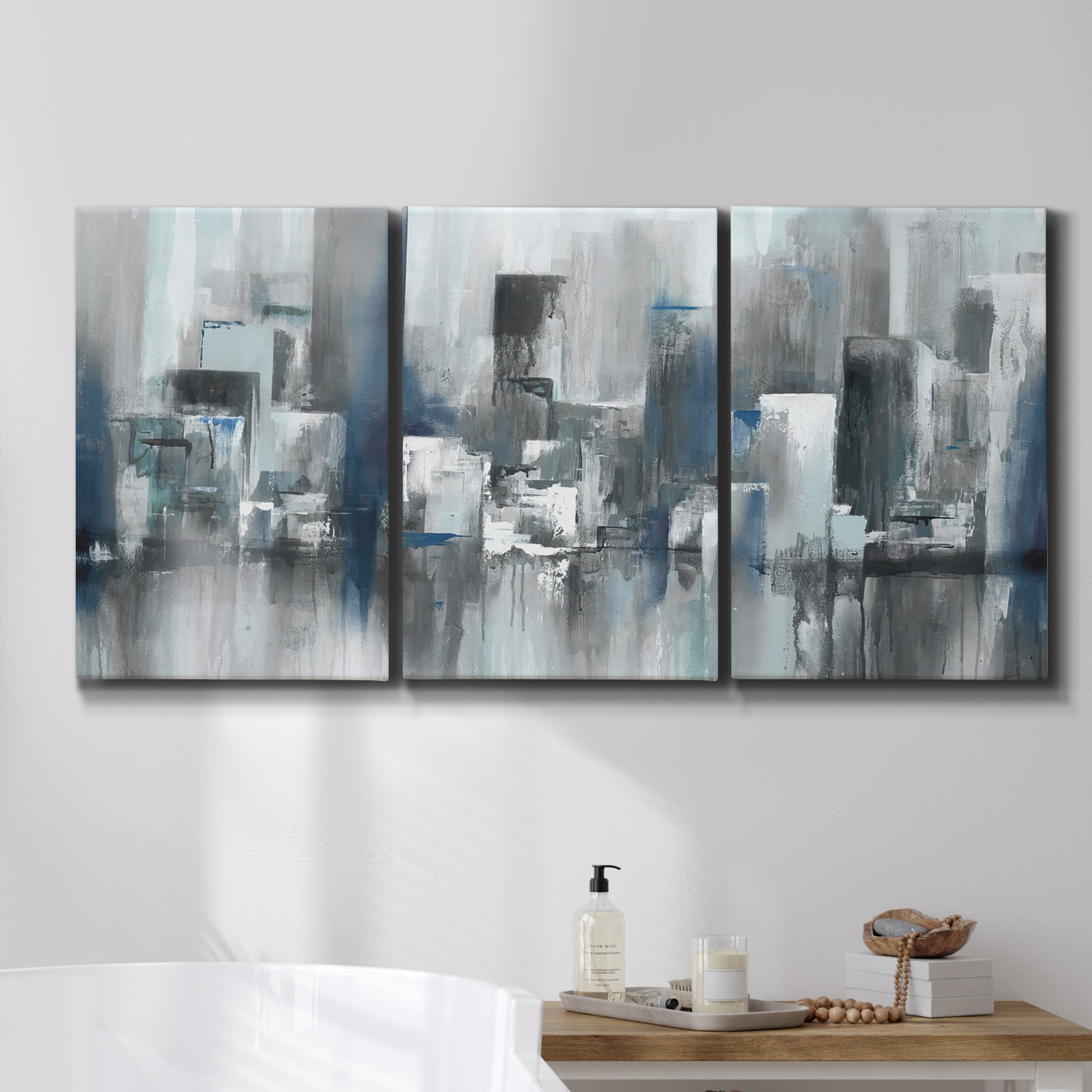 Three-panel canvas wall art featuring urban cityscape rendered in blue tones, displayed in a bathroom above a bathtub.